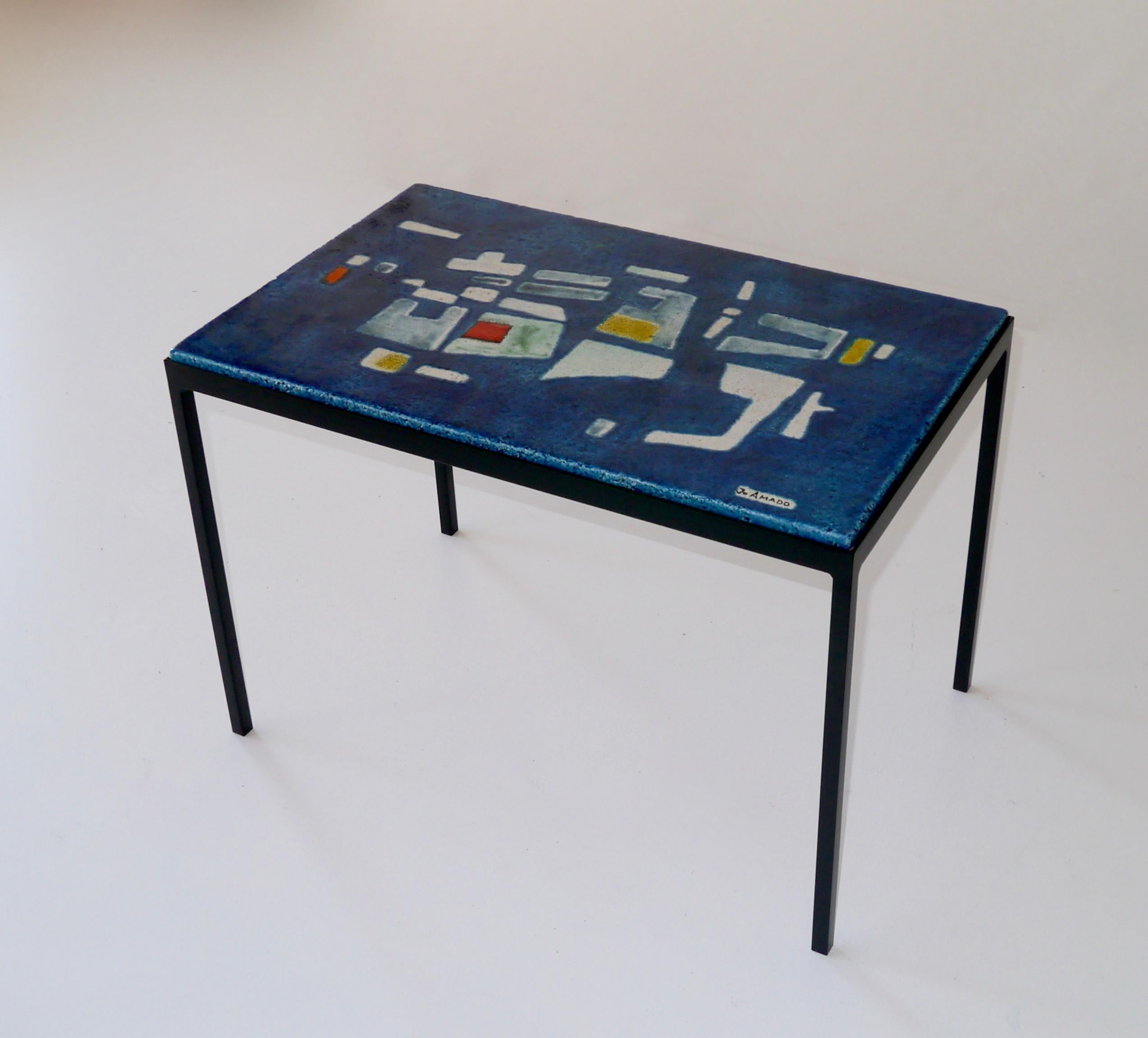 Plateau émaillé en terre cuite aux motifs graphiques posés sur une structure en fer forgé.
Signé 