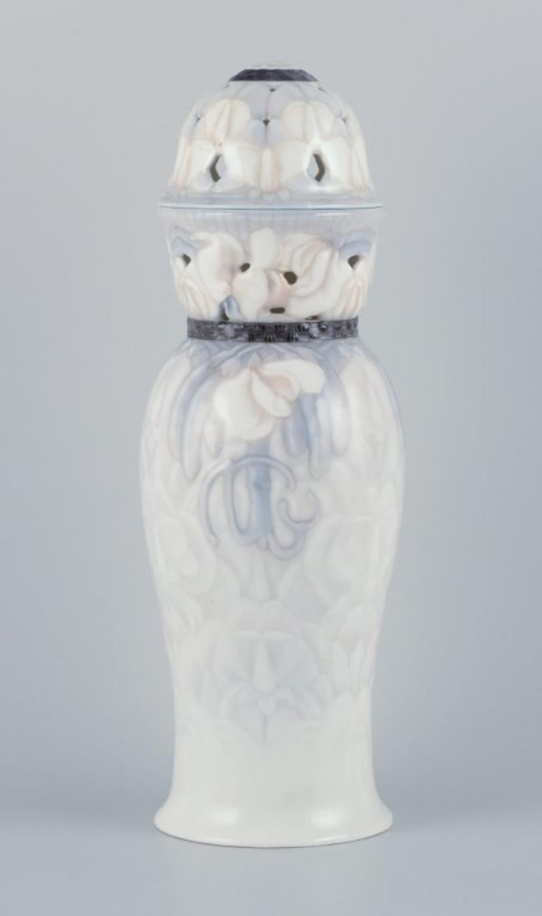 Jo Hahn Locher for Bing & Grøndahl.
Large and impressive Art Nouveau vase in porcelain. 
Openwork at the top and lid.
Ca. 1900.
Model number 412.
In excellent condition.
First factory quality.
Dimensions: H 34.0 cm x D 10.0 cm.