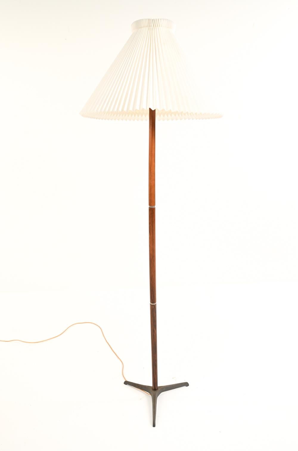 A Danish mid-century rosewood floor lamp designed by Jo Hammerborg with accordion style paper shade and cast iron tripod base. Featuring rosewood body with steel rings.
