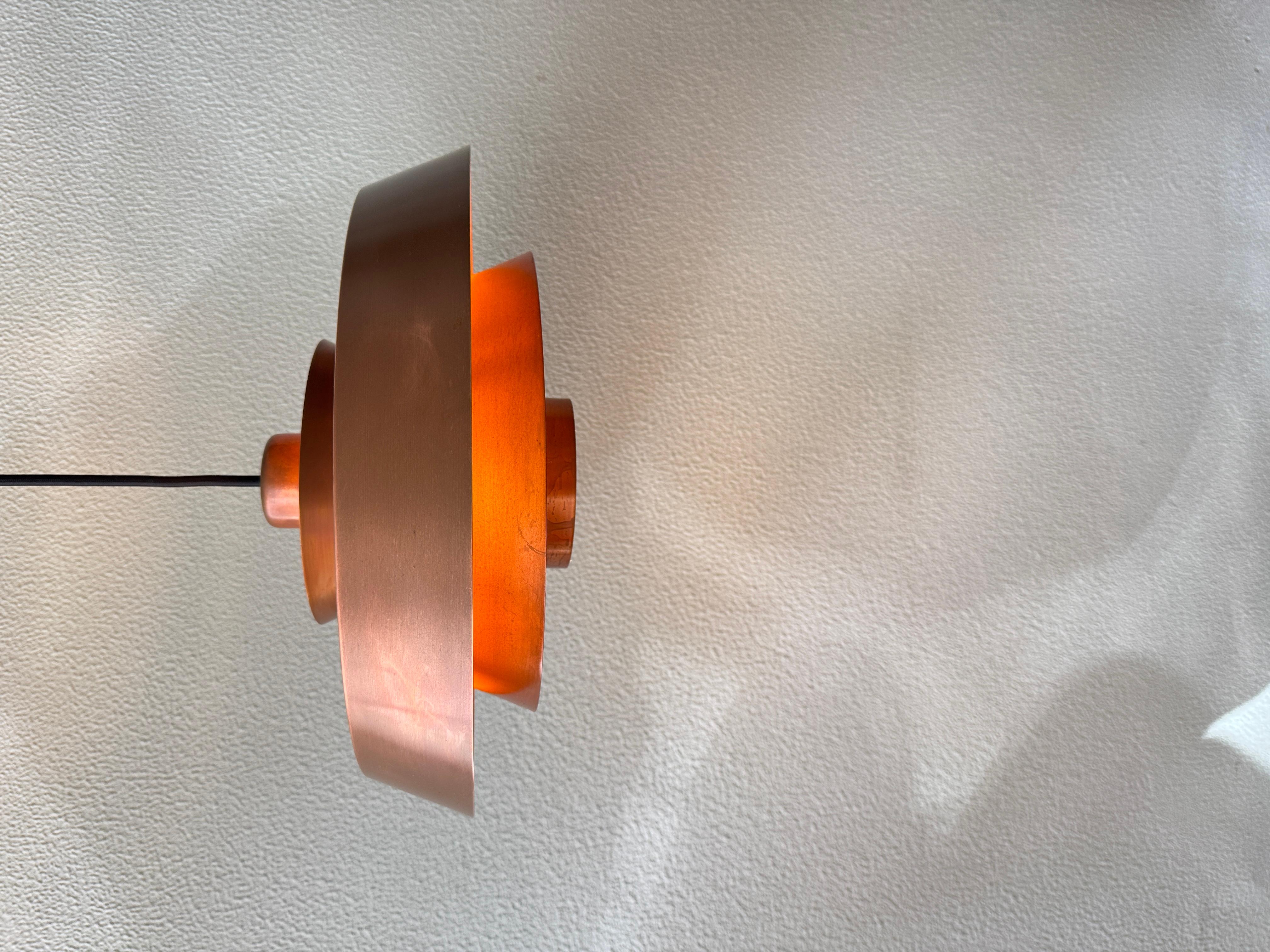 This “Nova” ceiling lamp, designed by Jo Hammerborg for Fog & Mørup in Denmark during the 1960s, exemplifies the sculptural precision and functional elegance that define Scandinavian modern lighting. Crafted in brushed copper with a beautifully