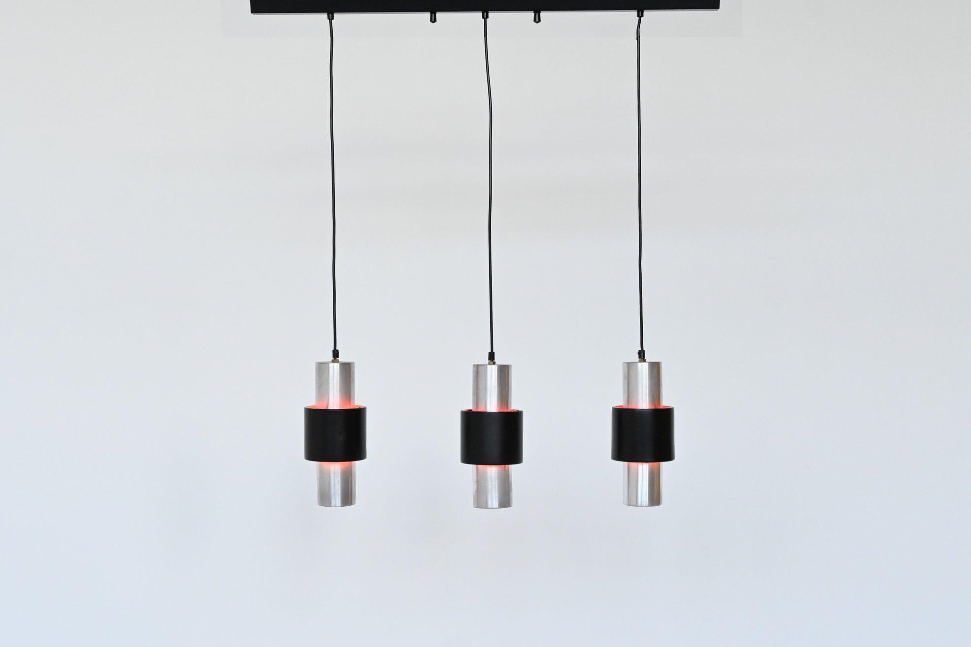 Beautiful set of three pendant lamps designed by Jo Hammerborg and manufactured by Fog and Morup, Denmark 1967. The lamps are made of aluminium with a black lacquered outer cylinder. The inside of the cylinder is lacquered in red so it emits a very
