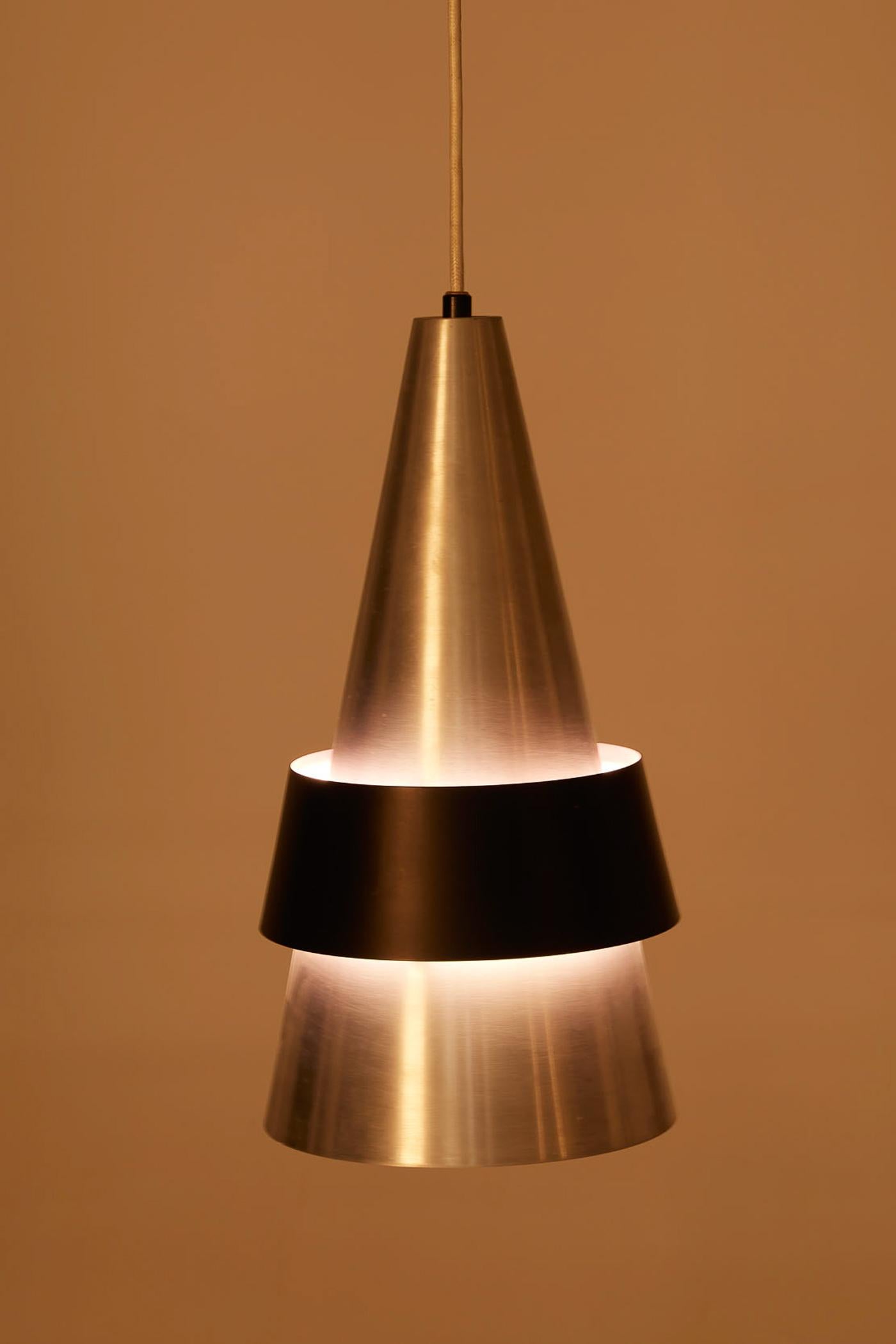 Suspension Corona du designer danois Jo Hammerborg pour Fog & Mørup, datant des années 1960. Le réflecteur conique est en métal brossé avec un anneau en métal laqué noir. Très bon état.
DV430-DV431