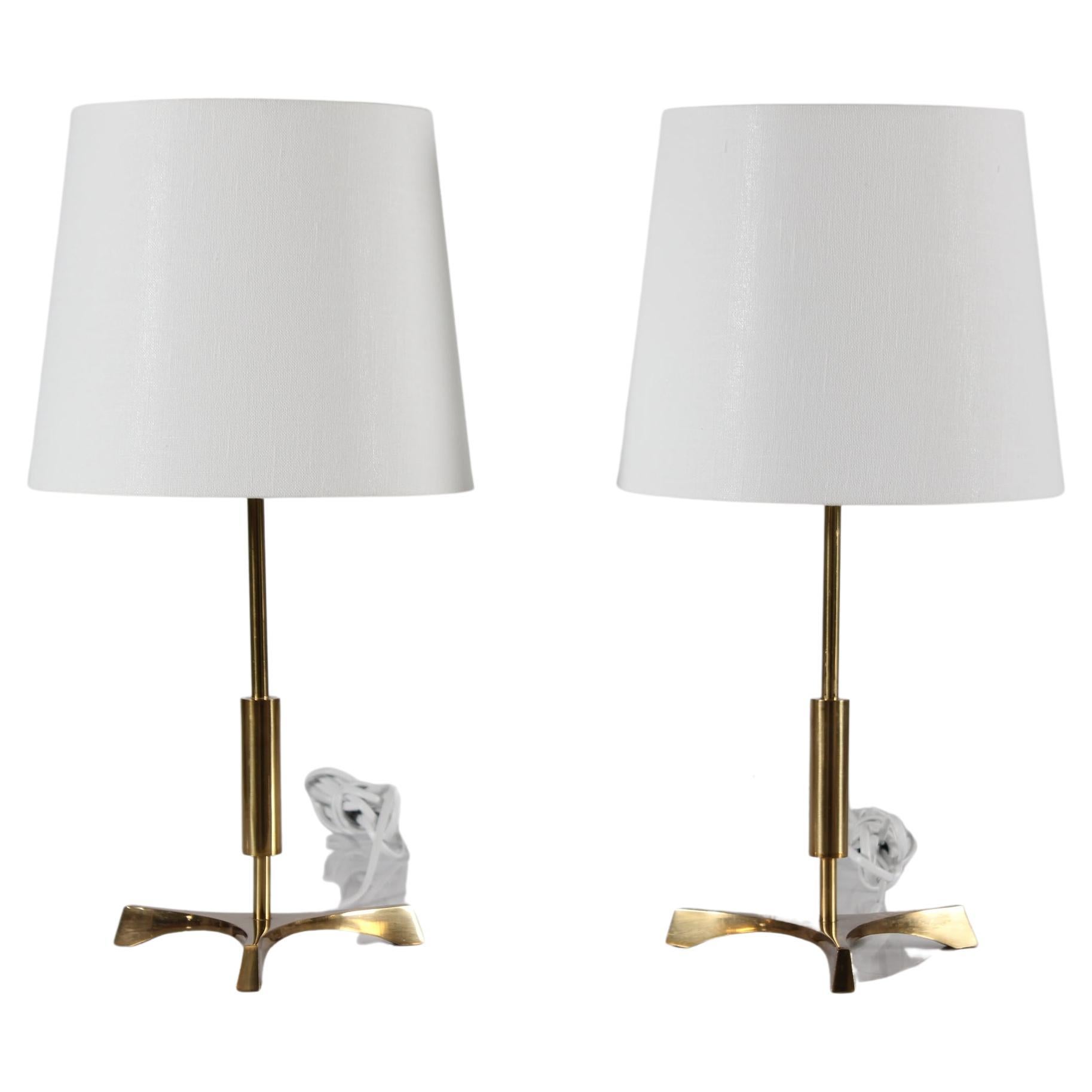 Pair of mid-century Danish tripod table lamps in Jo Hammerborg style.
The lamps are made of brass in the 1960s

Included is a pair of new lampshades designed in Denmark.
The shade is made of woven fabric with some texture and the color is