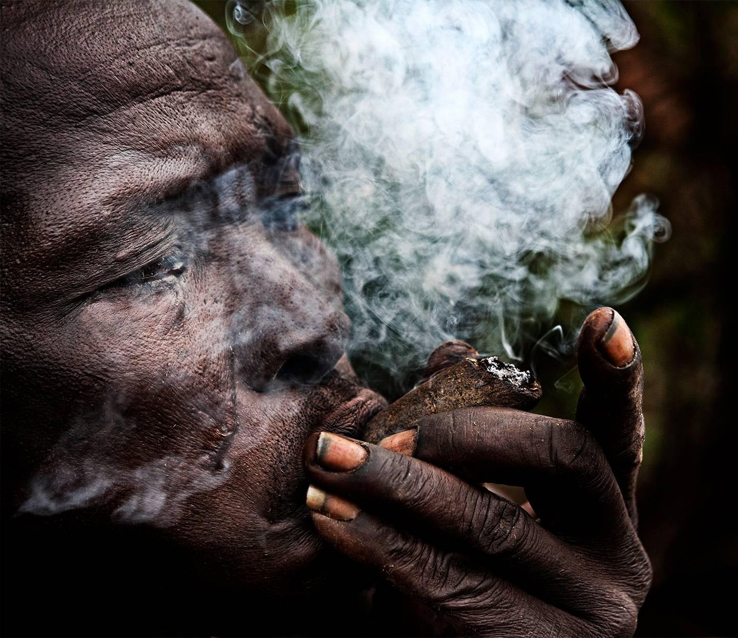 Joachim Schmeisser Portrait Photograph – Hadzabe, Menschen, Rauch, Farbfotografie, Feuer, Ägypten, Bushman