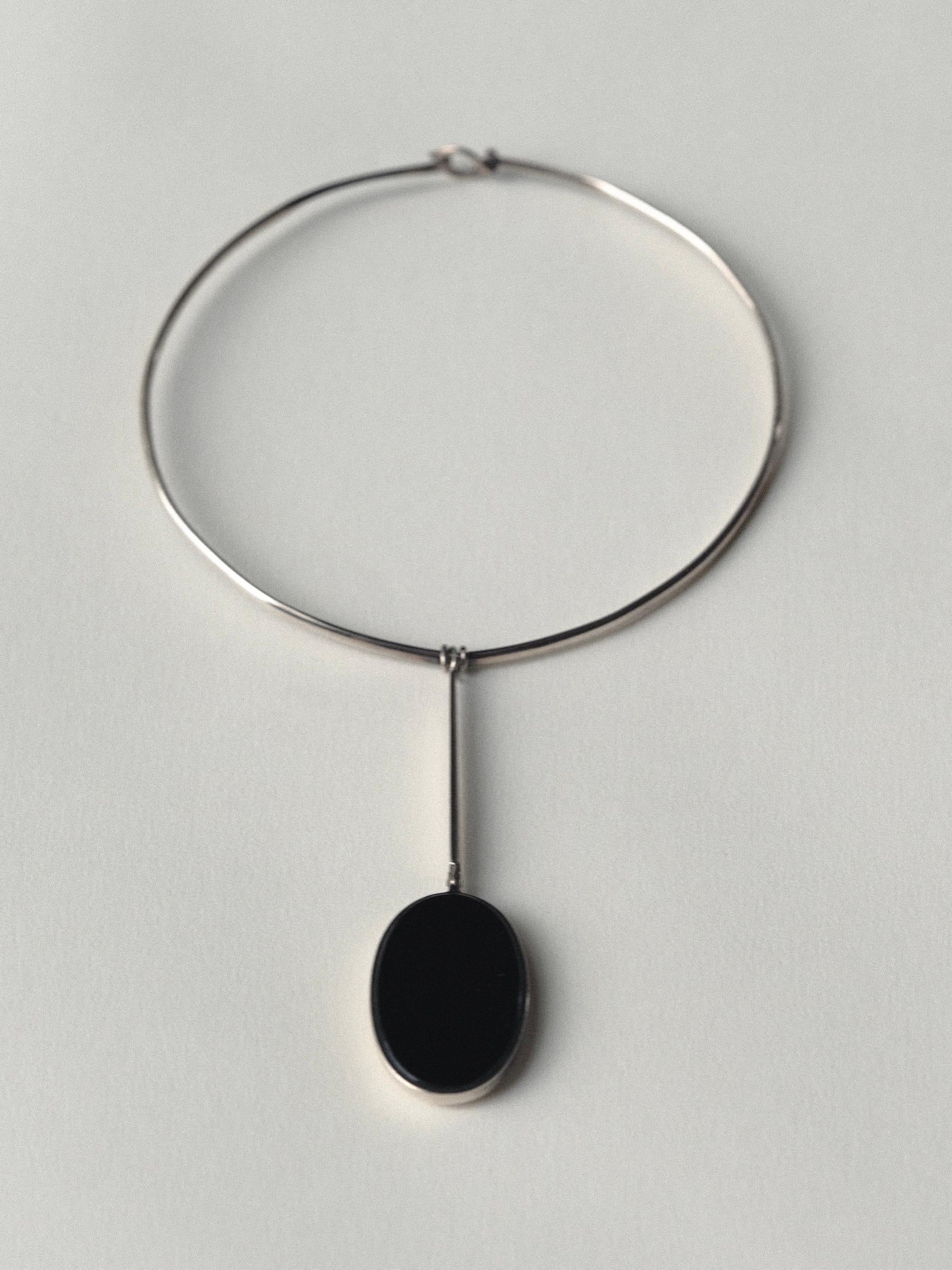 Silver Collar Drop Necklace by designer Joachim S'paliu
Oval cut black onyx stone set in silver
Articulates front to back at collar and stone
Handwrapped at collar to keep stationary
Shiny, smooth onyx at front
Bevel with back of matte stone at back