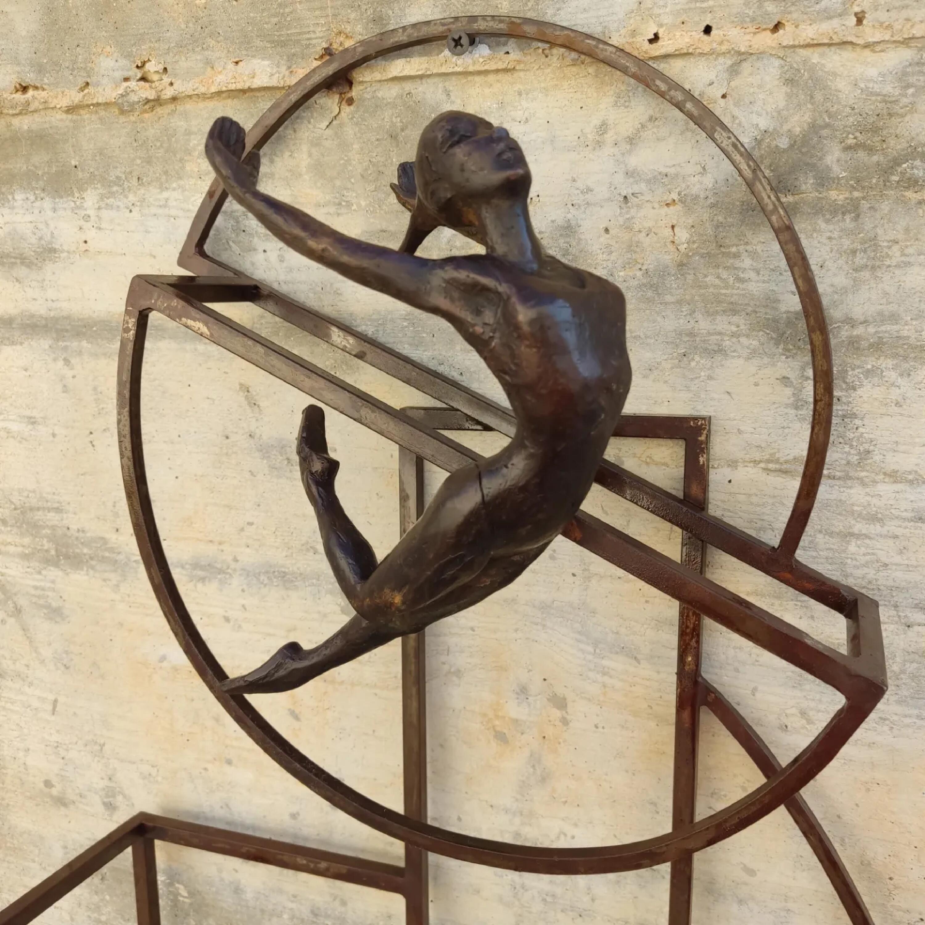 Hop is bronze sculpture wall table sculpture, it is connected to a steel base. The sculpture depicts human figures in a dynamic pose, as if caught in mid-movement.  The Dynamic composition of the sculpture gives the impression of being caught in a