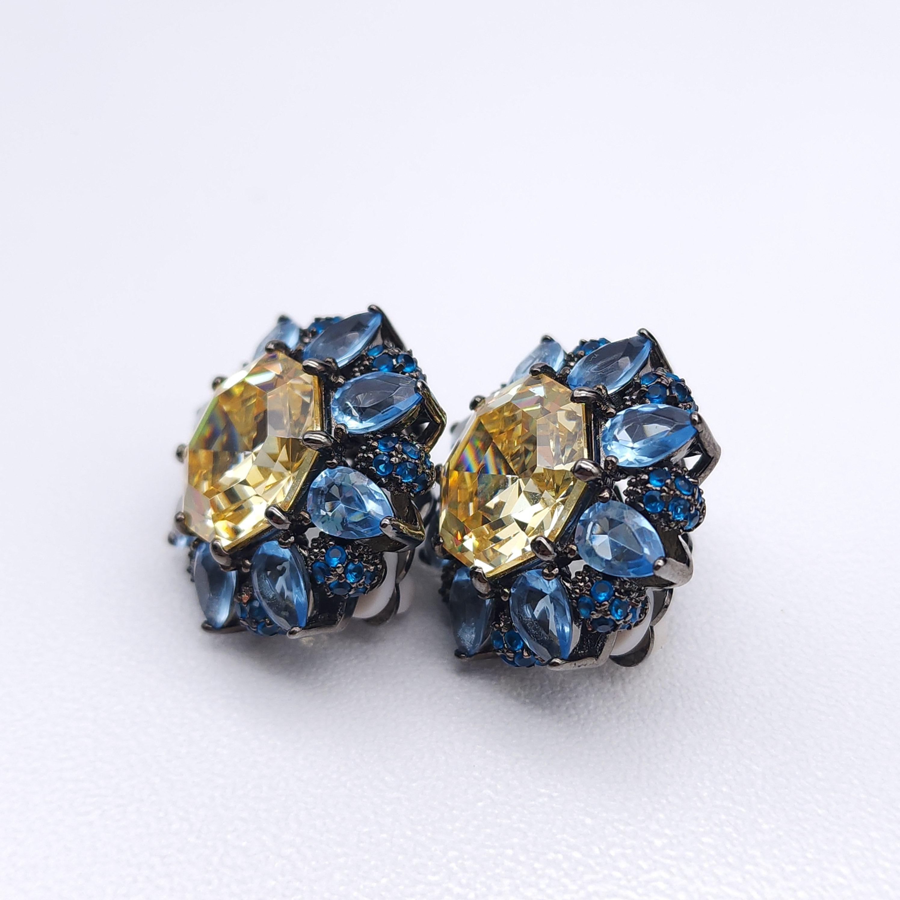 A striking pair of Joan Boyce statement earrings! These dazzling clip-ons are crafted in a dazzling floral-inspired design. The earrings feature a large, faceted champagne-hued crystal at the center, encircled by teardrop-shaped light blue crystals