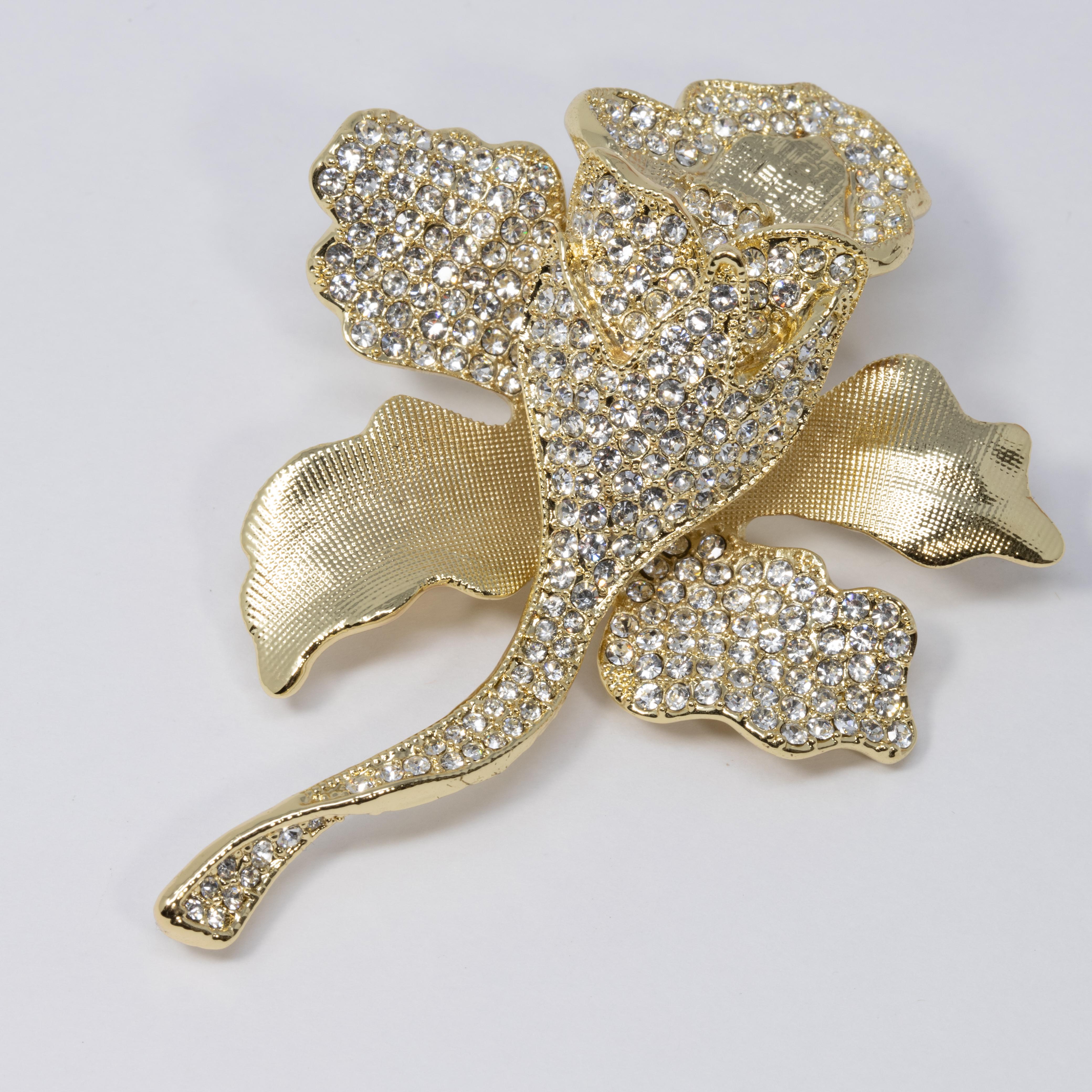 Eine extravagante Brosche von Joan Boyce. Die verschnörkelte, strukturierte, goldfarbene Blume ist mit klaren Pflasterkristallen verziert. Atemberaubend!

Markenzeichen: JB, CN