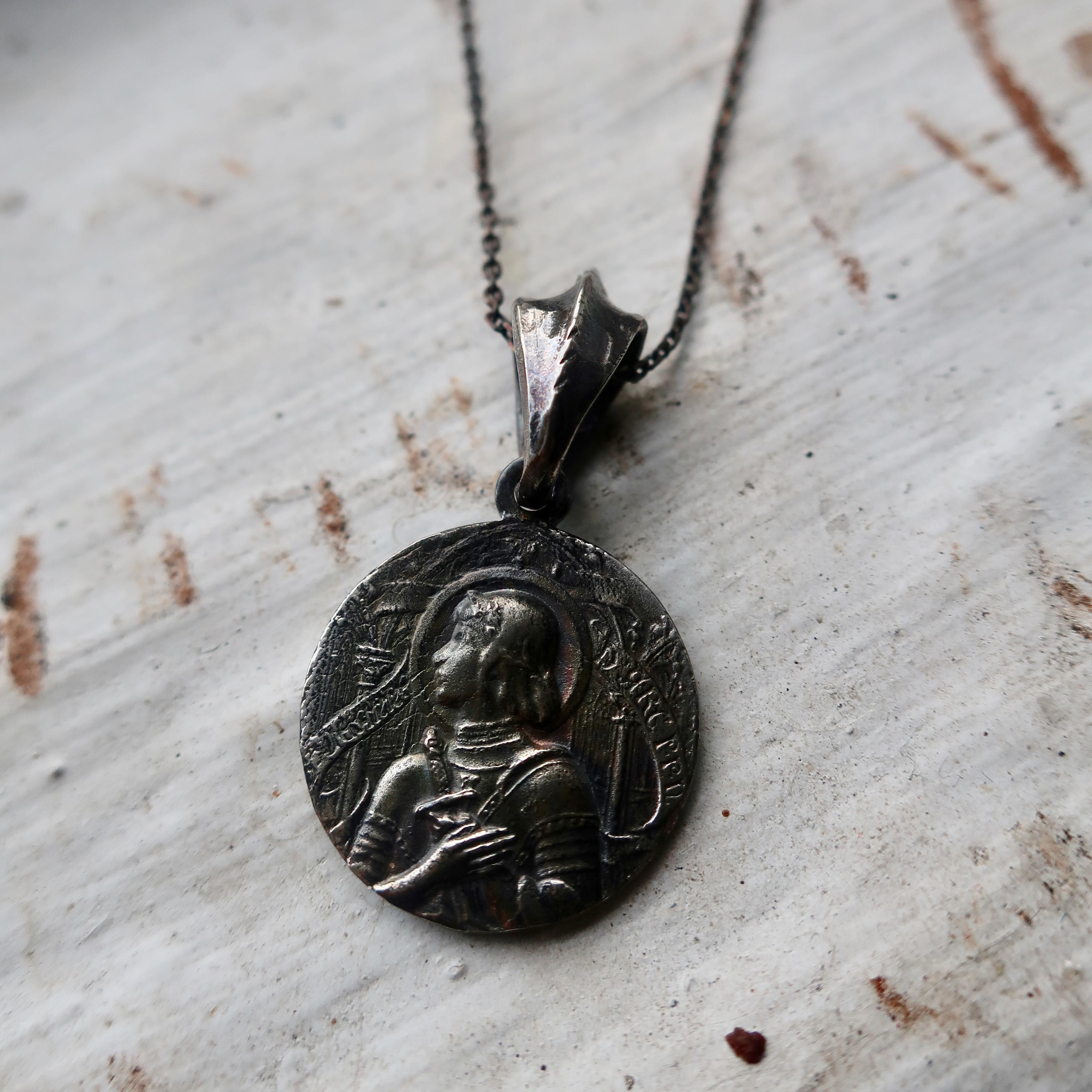 This piece features a vintage coin depicting Joan of Arc in 14k white gold and chain on a hand made bail. Cast in solid 14k white gold, this piece is oxidized to highlight the many engraved details on the front and back.  The coin is about 20mm