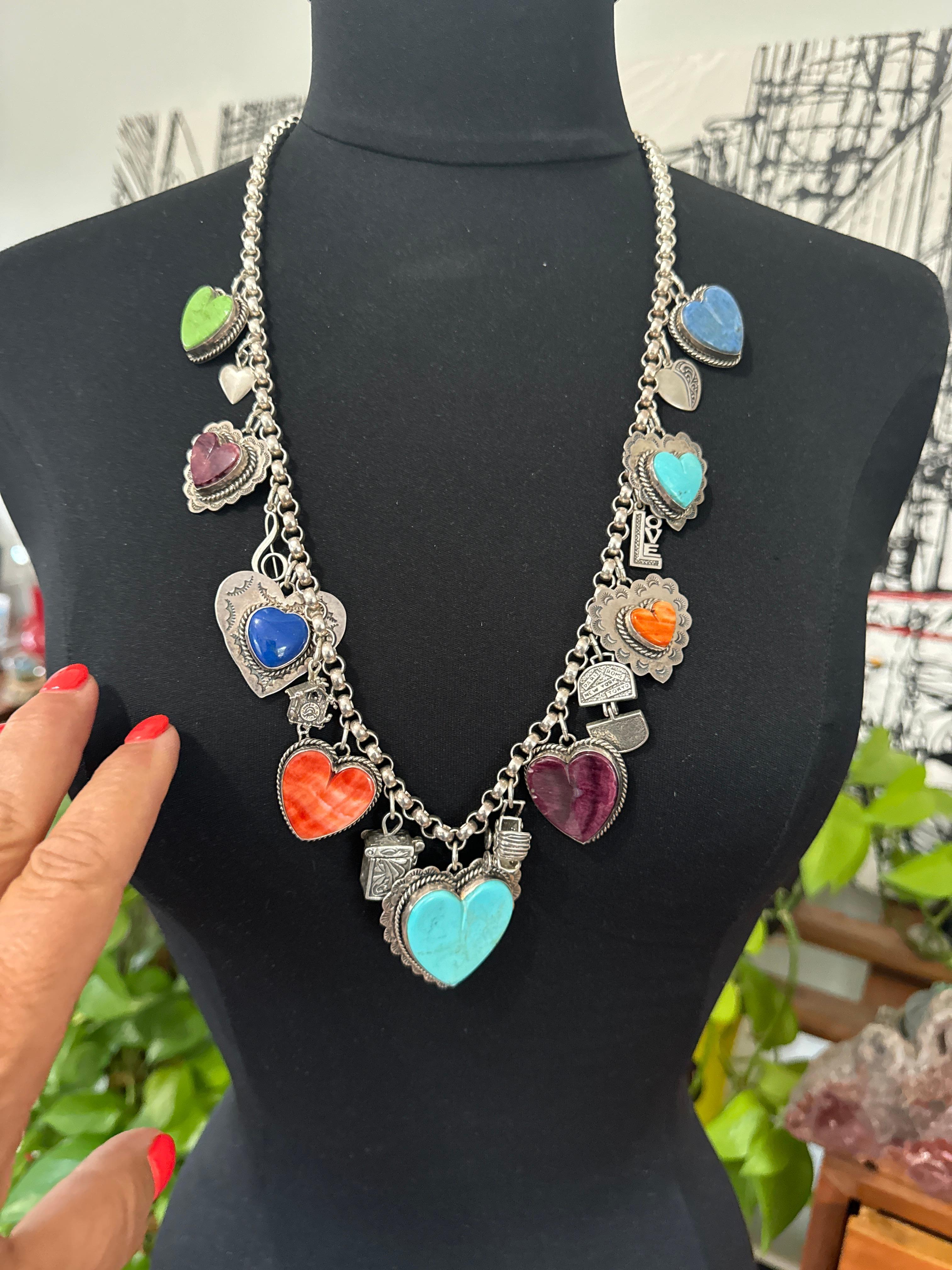 Este exquisito y coleccionable collar de corazón de doble cara de la diseñadora Joan Slifka está fabricado en plata de ley maciza y adornado con una serie de vibrantes colgantes de corazón de piedras preciosas. Midiendo  esta sustanciosa pulsera