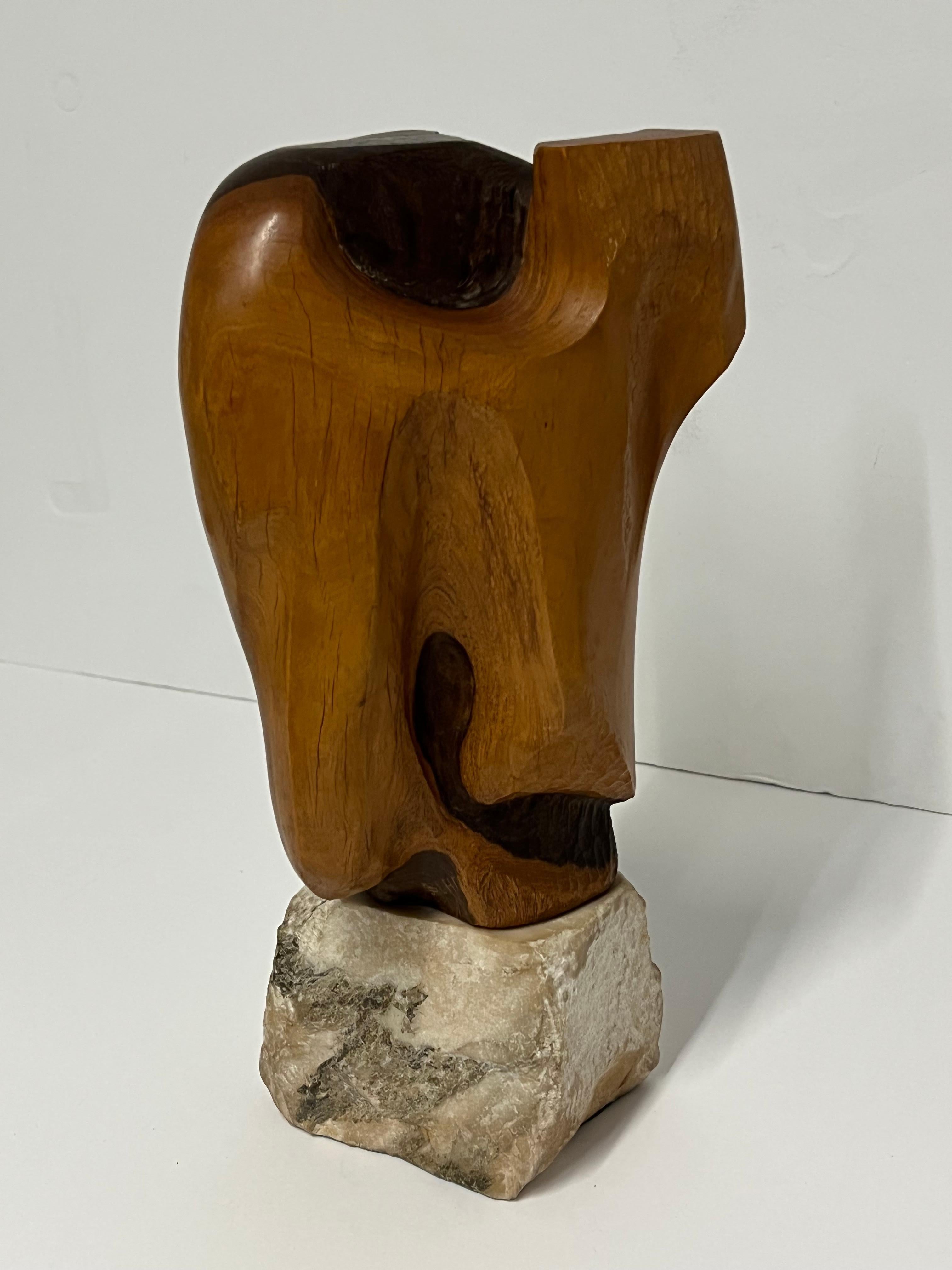 This abstract expressionist wood sculpture sits on a large white marble rock block.

Joan Strauss Carl was a Los Angeles artist, teacher, and humanitarian activist.  She was a past president of the Los Angeles Art Association and has left a