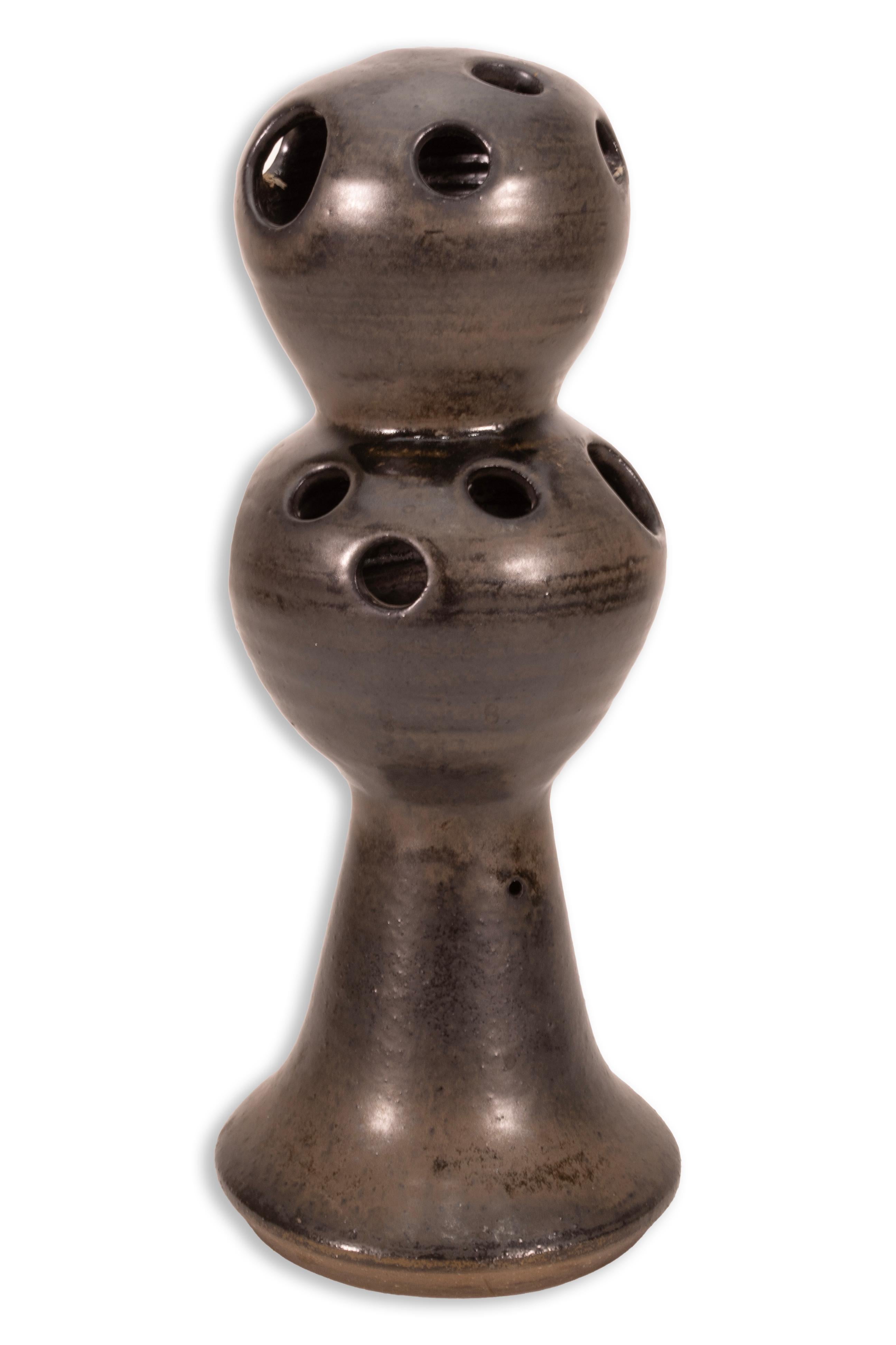 Ce petit pot à herbe émaillé signé par Joanna Price a une forme étrange mais qui attire l'attention, orné de petits trous couvrant la moitié supérieure du pot et d'une belle finition gunmetal foncé. Sa forme intéressante permet d'engager la