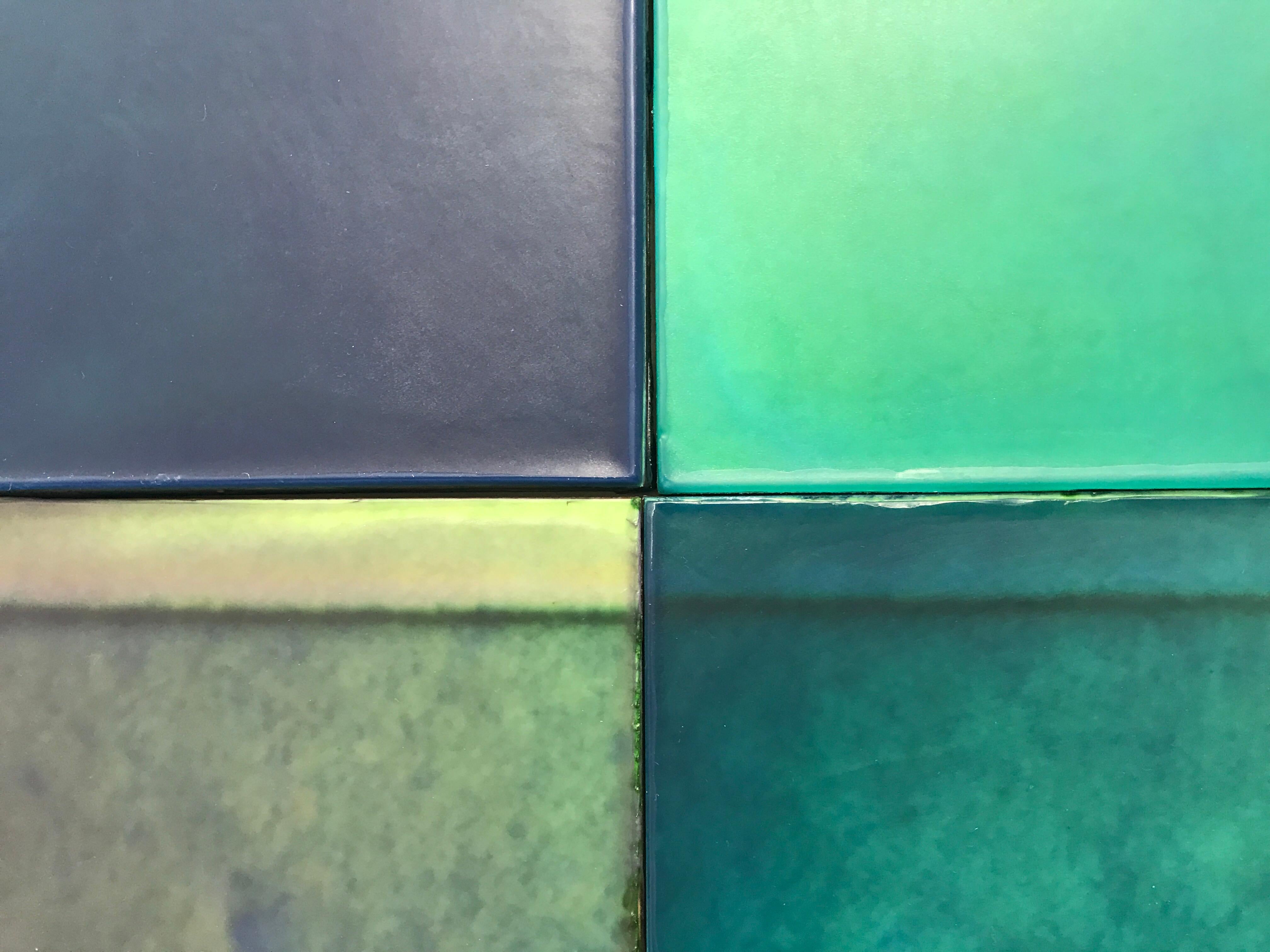 This wall piece is composed of 24 cast wax panels.  The abstracted image imbedded in the work is a photograph of the packing for Estee Lauder Modern Muse Perfume. Vivid emerald green and blue tones are created in Joanne Ungar's unique poured wax
