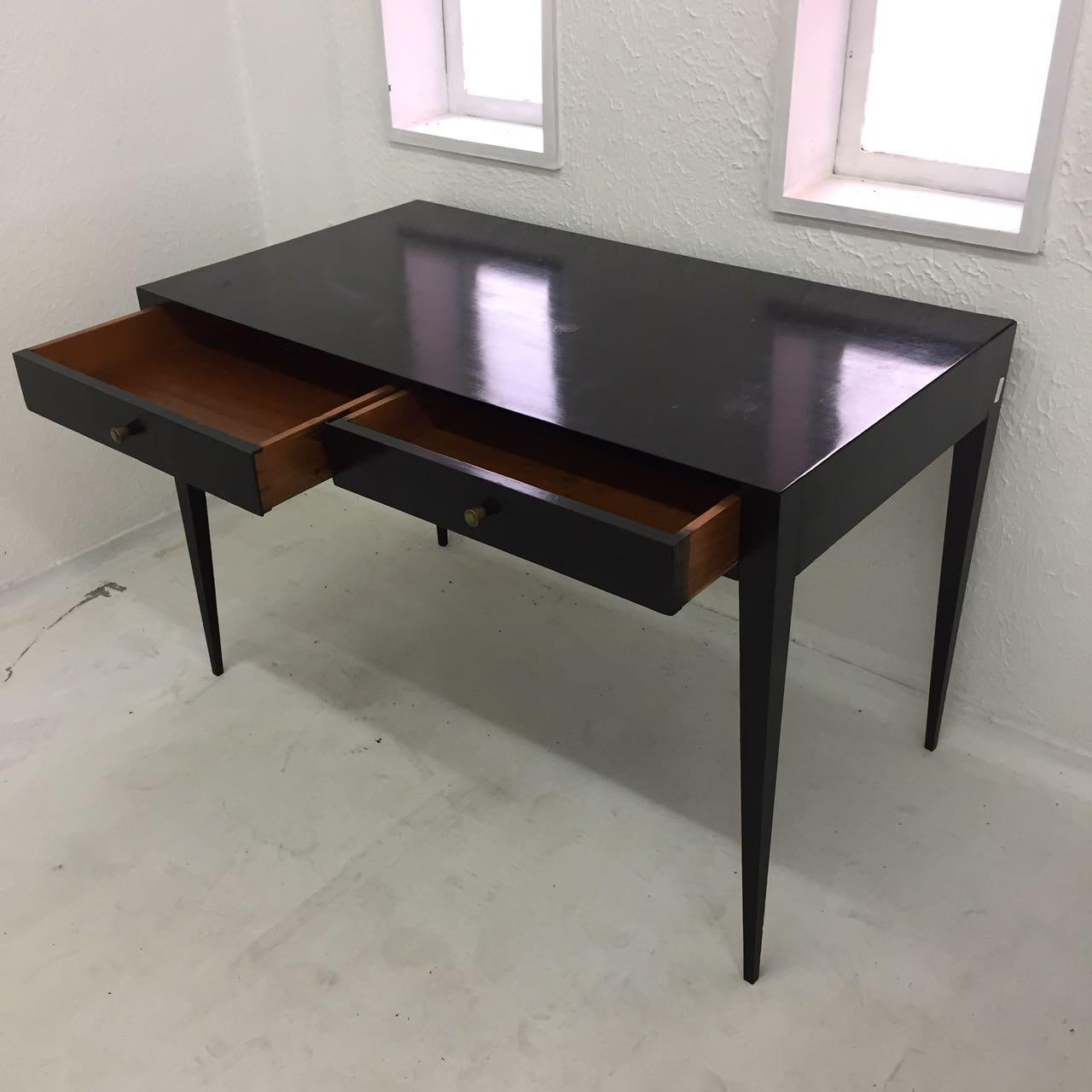 Freestanding Joaquim Tenreiro desk in ebonized wood with two integrated drawers. Designed circa 1950, Brazil. An iconic piece of furniture from the golden age of Brazilian design.