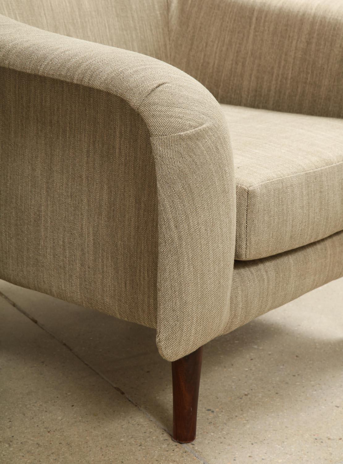 Beautifully sculpted upholstered seat forms displaying an interesting tension between bulbous form and the seek detailing. Conical legs of Jacaranda.