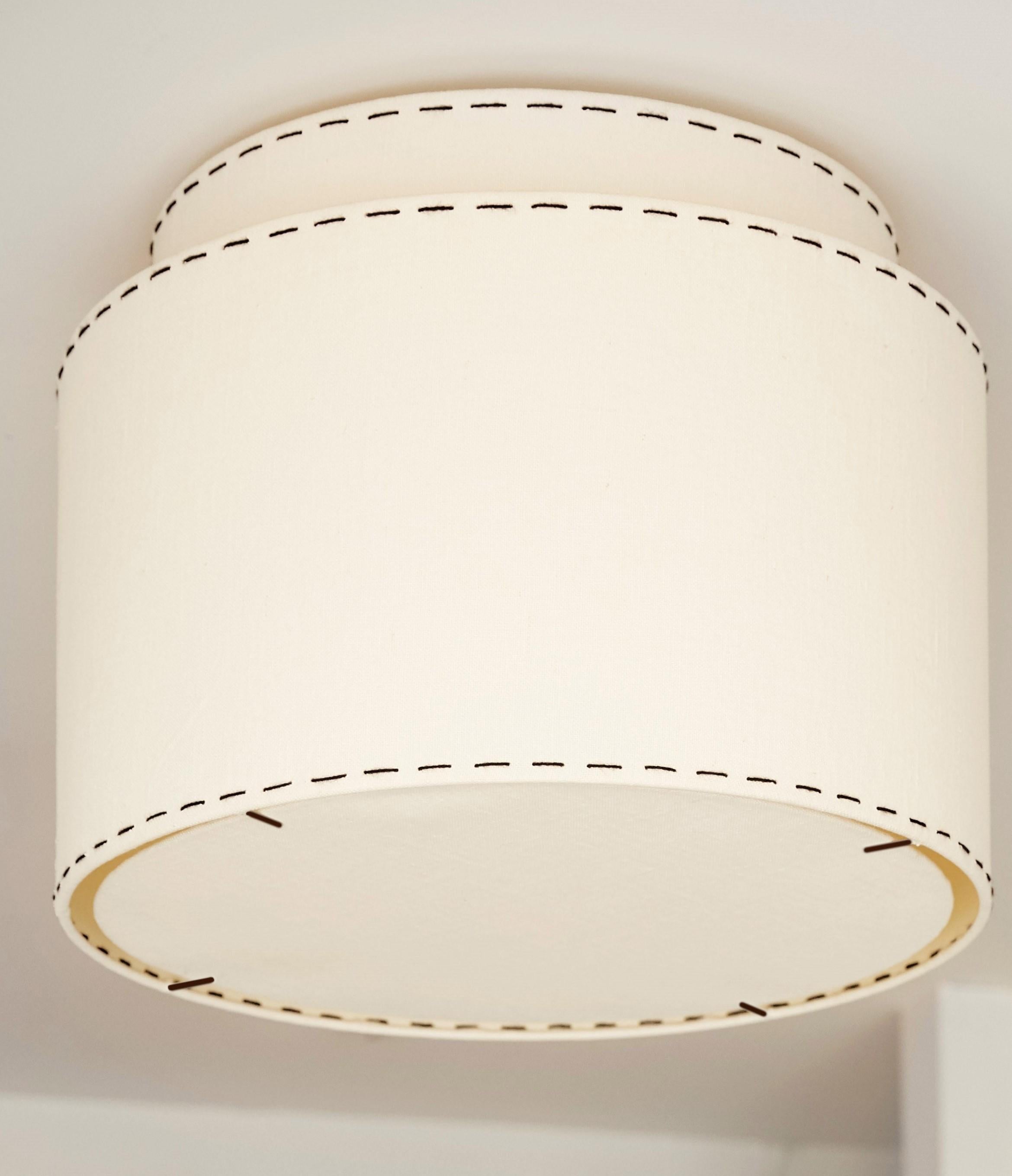 This classic, tailored, double ceiling lamp, is inspired by old Hollywood and menswear, reminiscent of the 1940s and the early simplicity of Art Deco and 20th Century Modern. Its clean shape is the perfect foil for our signature stitching to both