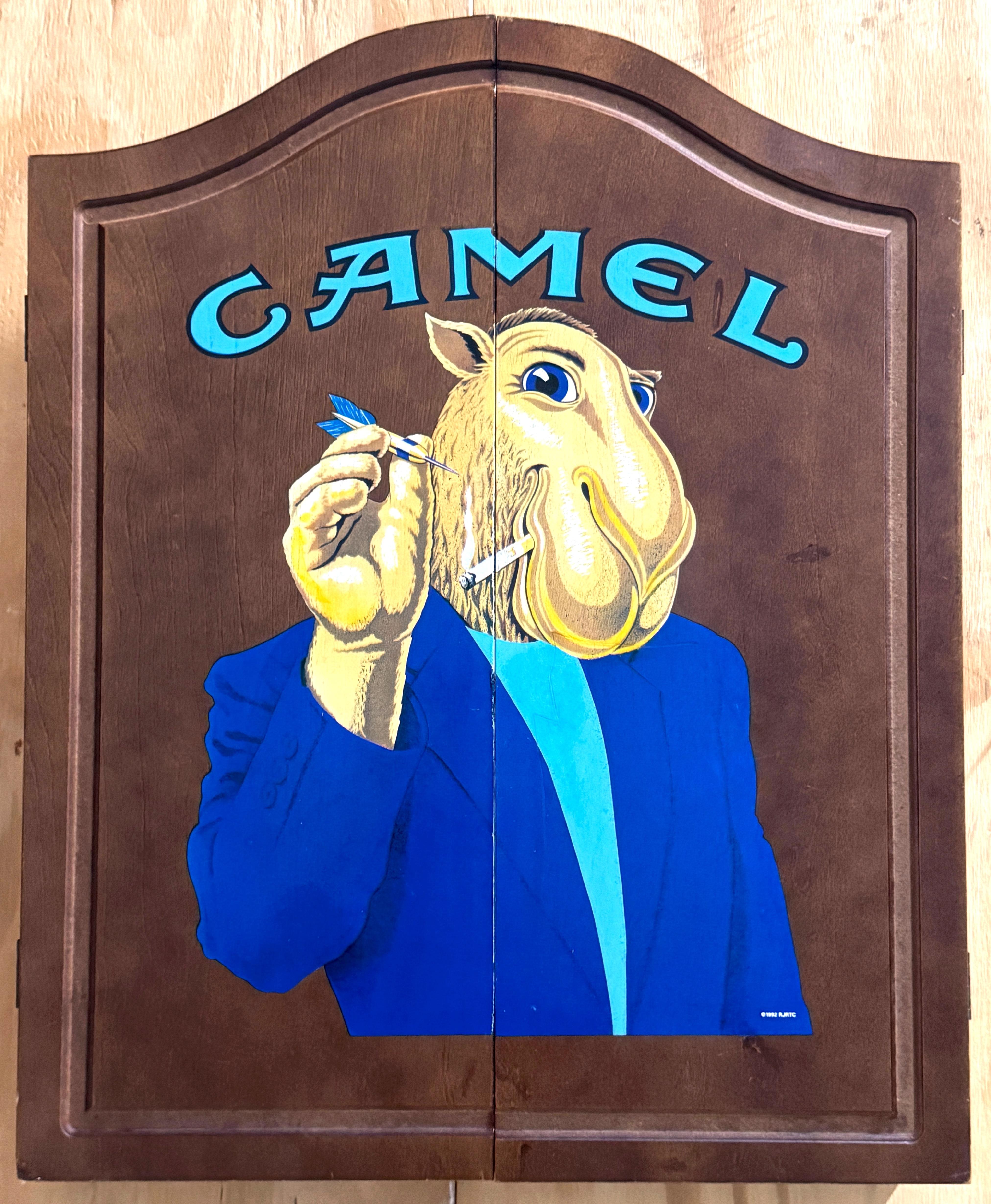 Joe Camel Dartboard Cabinet with Score Panels 1992, Unused, USA, Copyright 1992

This rare, vintage Joe Camel Dartboard Cabinet from 1992 is a quintessential piece of 1990s smoking/sporting memorabilia, perfect for any man cave or vintage
