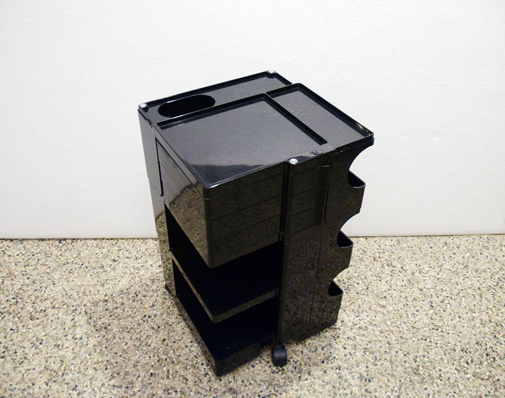 Boby storage trolley designed by Joe Colombo for Bieffeplast, 1970s.

In black plastic material, on wheels with six open compartments, three drawers that can be opened like a compass and an upper shelf for placing objects.
Signature engraved on the