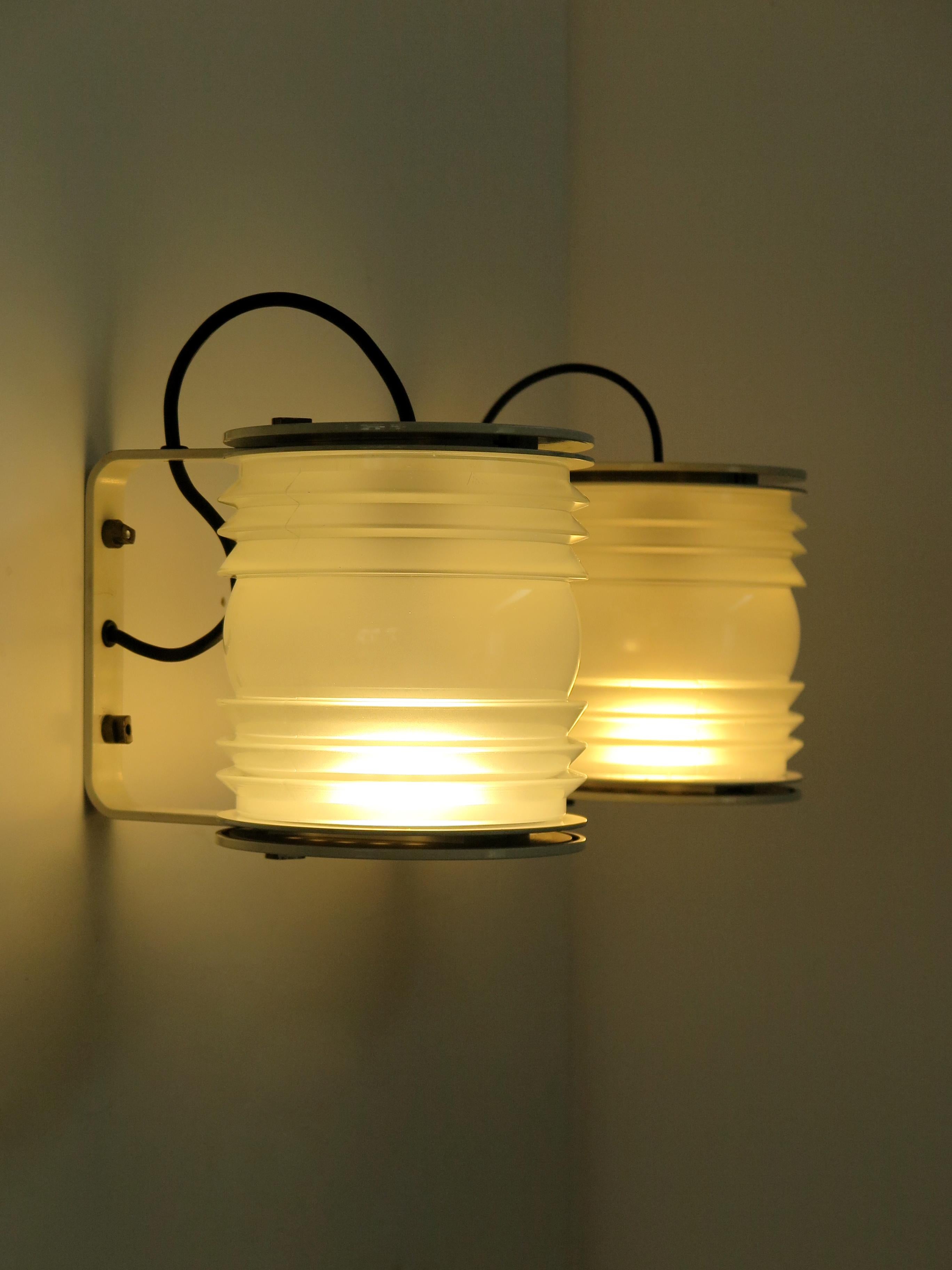 Italian midcentury modern design set of two sconces wall lamps “Fresnel” model designed by Joe Colombo and produced by Oluce from 1760s with thick moulded opaque glass cylindrical diffusers and white lacquered metal frame, Italy 1960s

Please note