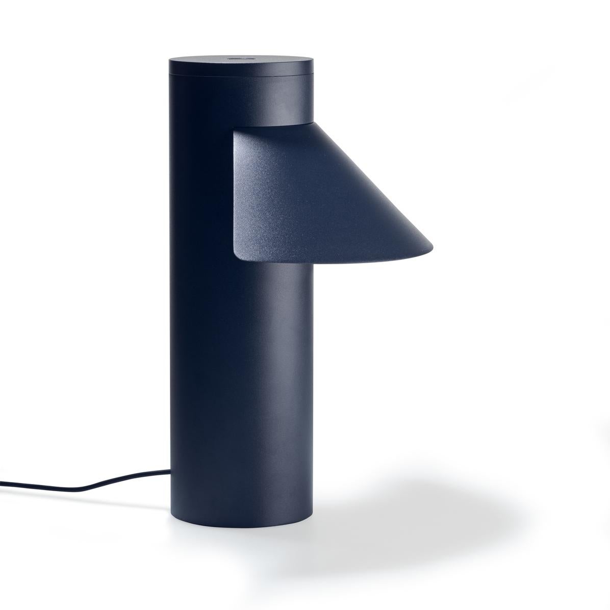 Table lamp designed by Joe Colombo in 1968. 

With its sleek yet optimistic clarity of form; a light, triangular shade seemingly floating off a weighty cylindric base, Italian design icon Joe Colombo’s table lamp nods to Asian heritage, the name