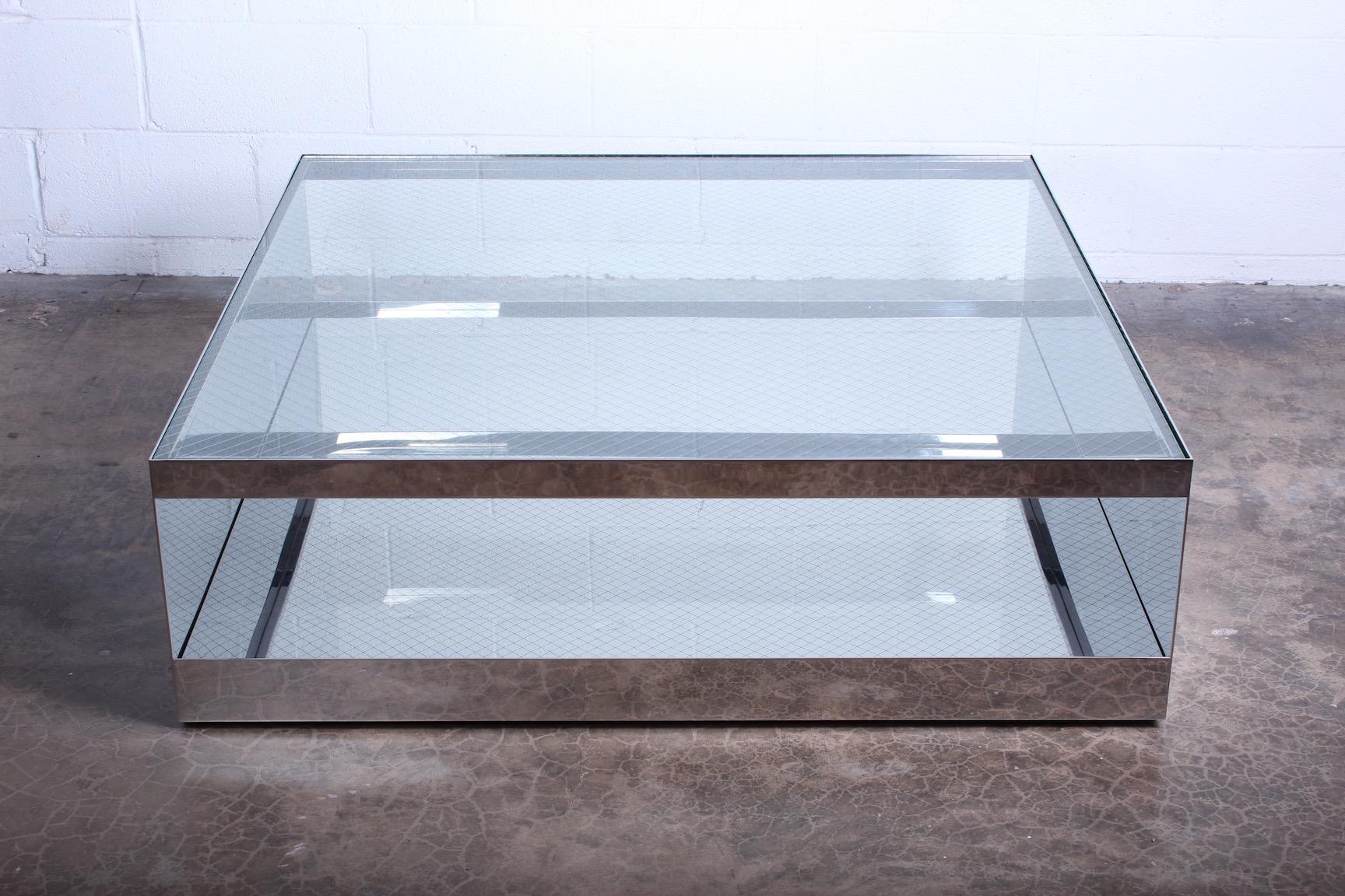 A polished stainless steel coffee table with safety glass top on casters. Designed by Joe D'urso for Knoll.