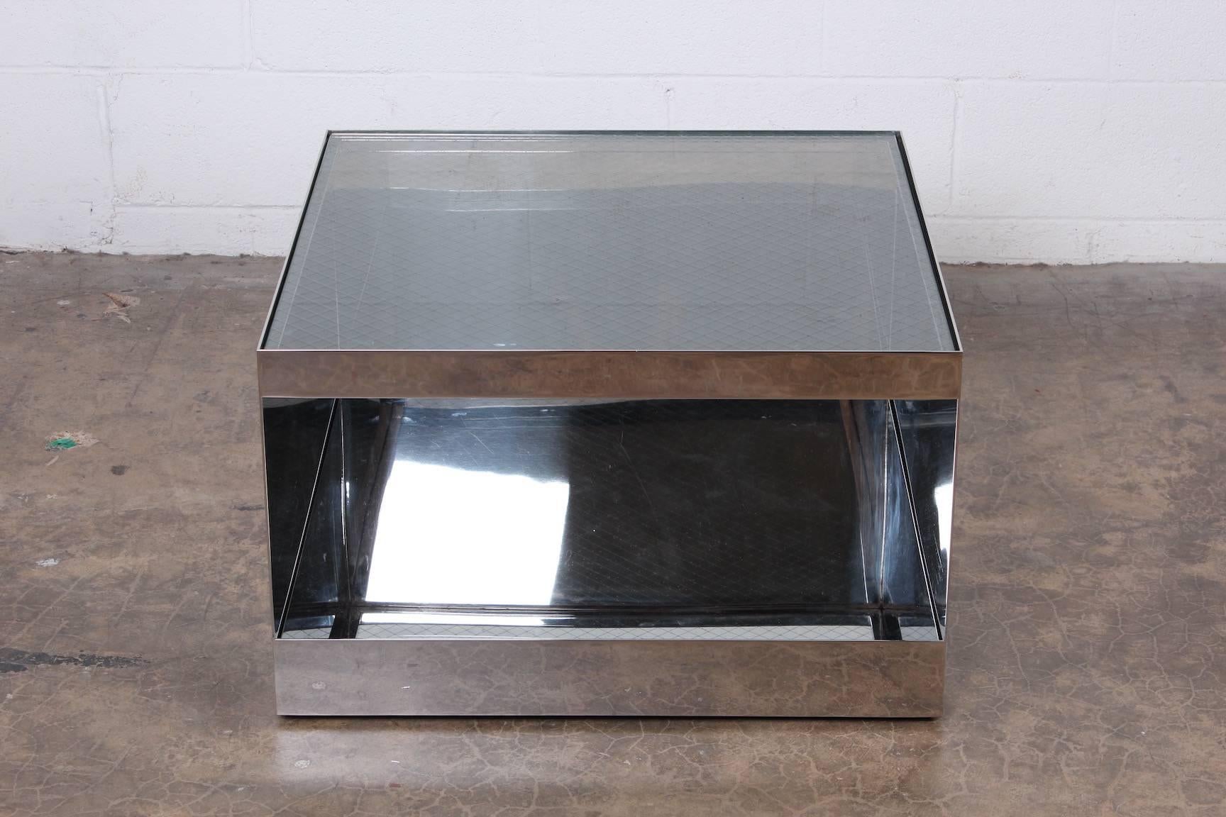 A polished stainless steel table with safety glass top on casters. Designed by Joe D'urso for Knoll.