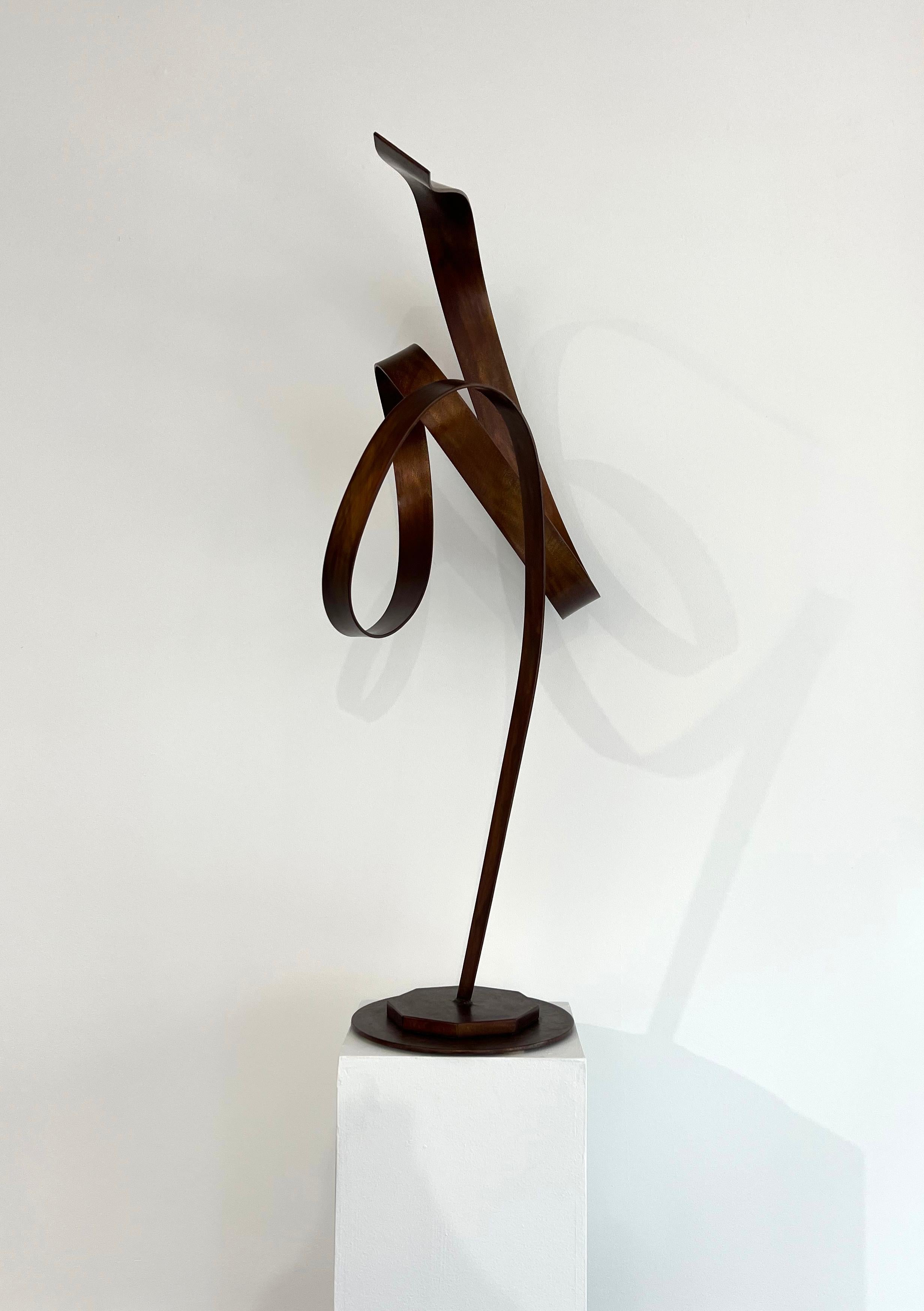 Cette sculpture abstraite de Joe Sorge est réalisée en acier avec une teinture orange et de la cire. Une seule bande d'acier s'étend vers le haut à partir d'une base, et se torde et se spirale en forme de ruban bouclé. La base du piédestal blanc