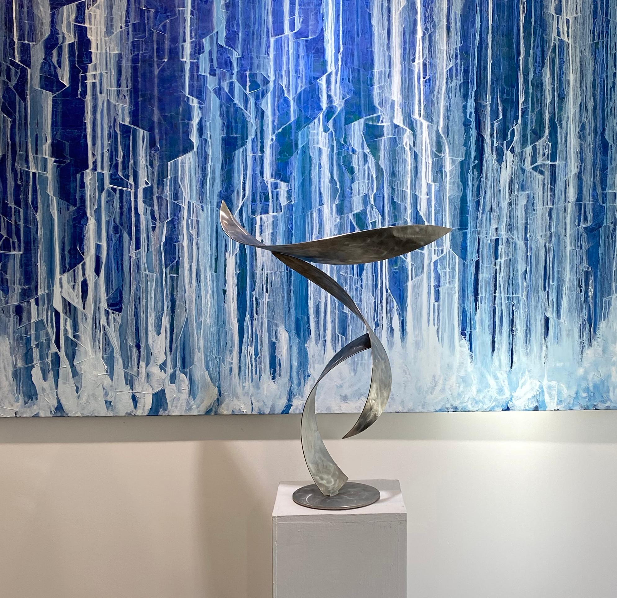 Diese mittelgroße abstrakte zeitgenössische Skulptur des Künstlers Joe Sorge ist aus Edelstahl gefertigt. Die Stahlstreifen, aus denen dieses Stück besteht, haben eine gebogene, konkave Form und eine schöne Textur. Das Werk wirft einzigartige