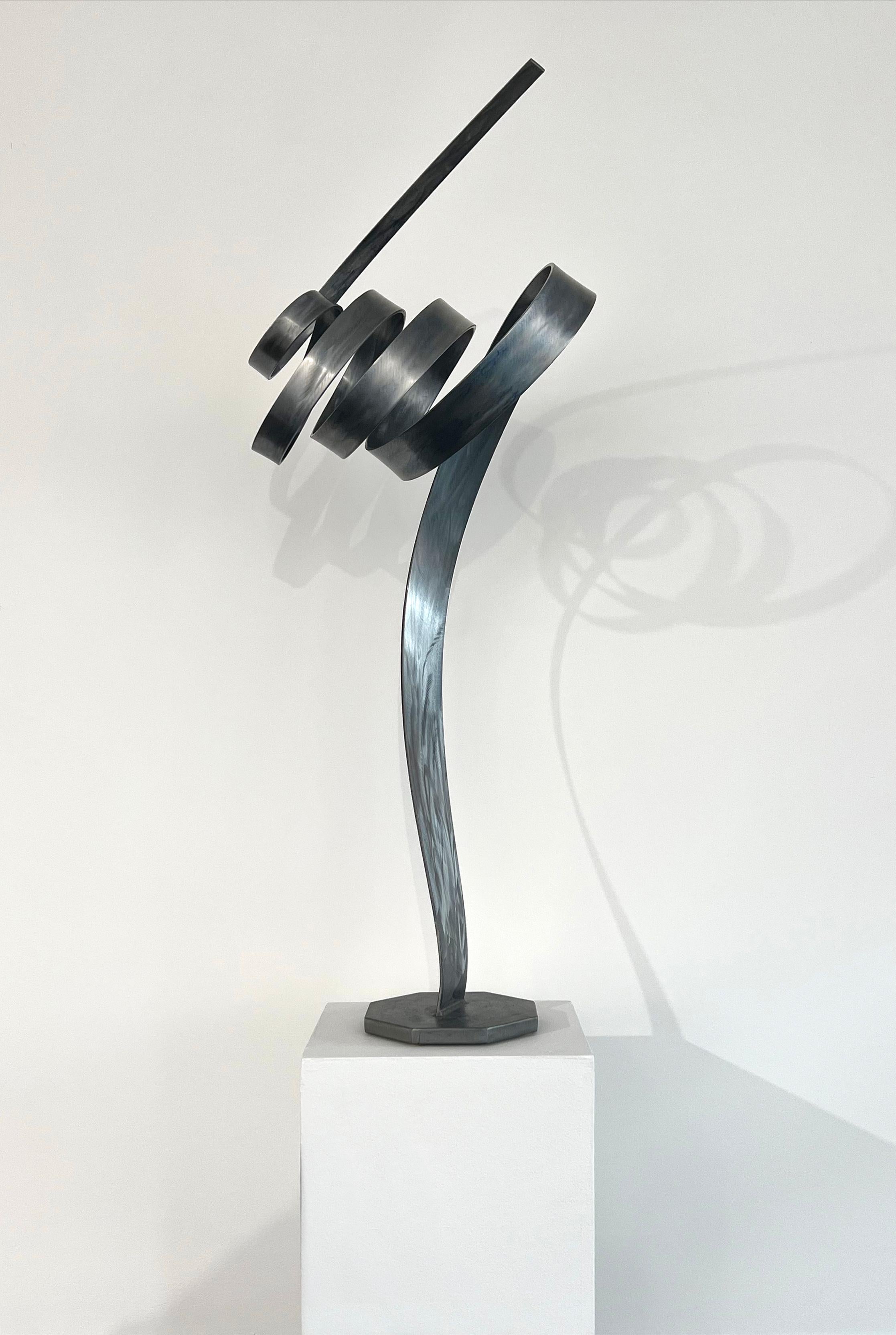 Questa scultura astratta di Joe Sorge è realizzata in acciaio e cera blu. Una singola striscia d'acciaio si estende da una piccola base d'acciaio, si avvolge a spirale diverse volte e poi si allunga di nuovo in modo rettilineo. La scultura è alta 43