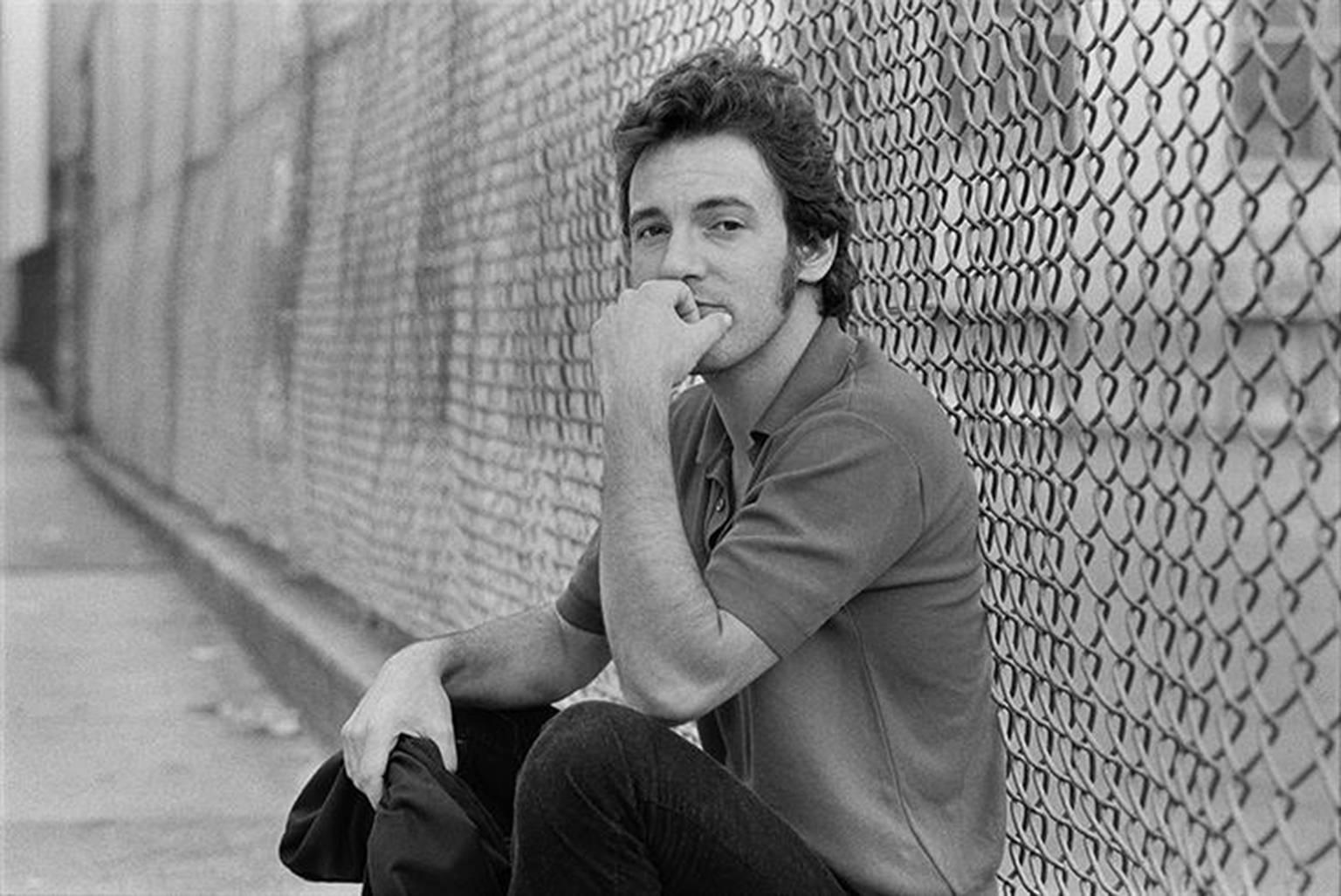 Joel Bernstein Black and White Photograph - Bruce Springsteen by Schoolyard Fence, NY Aug. 1979