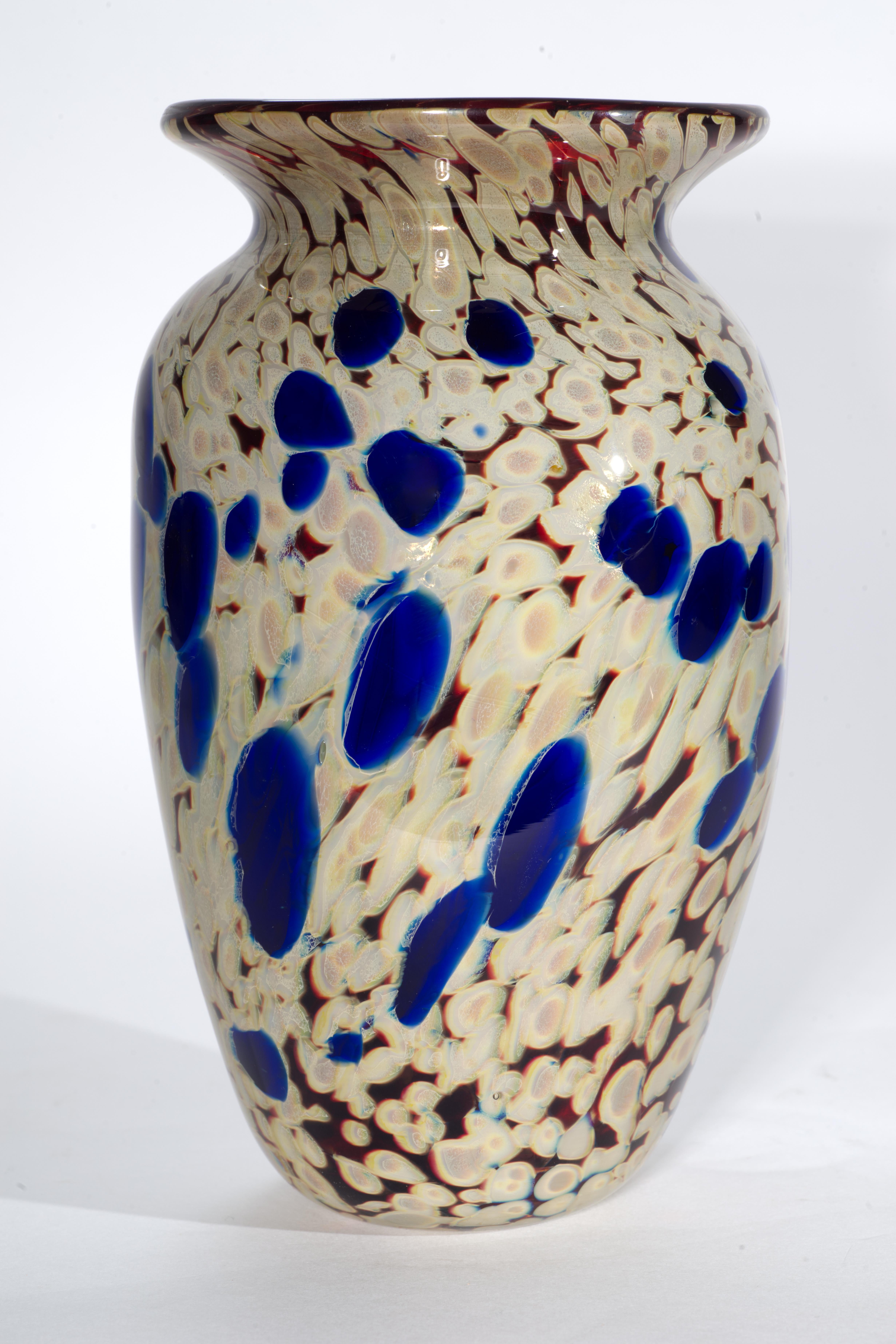  Il vaso in vetro fuso presenta un complesso nucleo di vetro colorato multistrato nei colori rosso rubino, beige, crema e blu cobalto intenso, racchiuso in vetro trasparente con la tecnica del sommerso. L'inclusione di pigmenti metallici negli