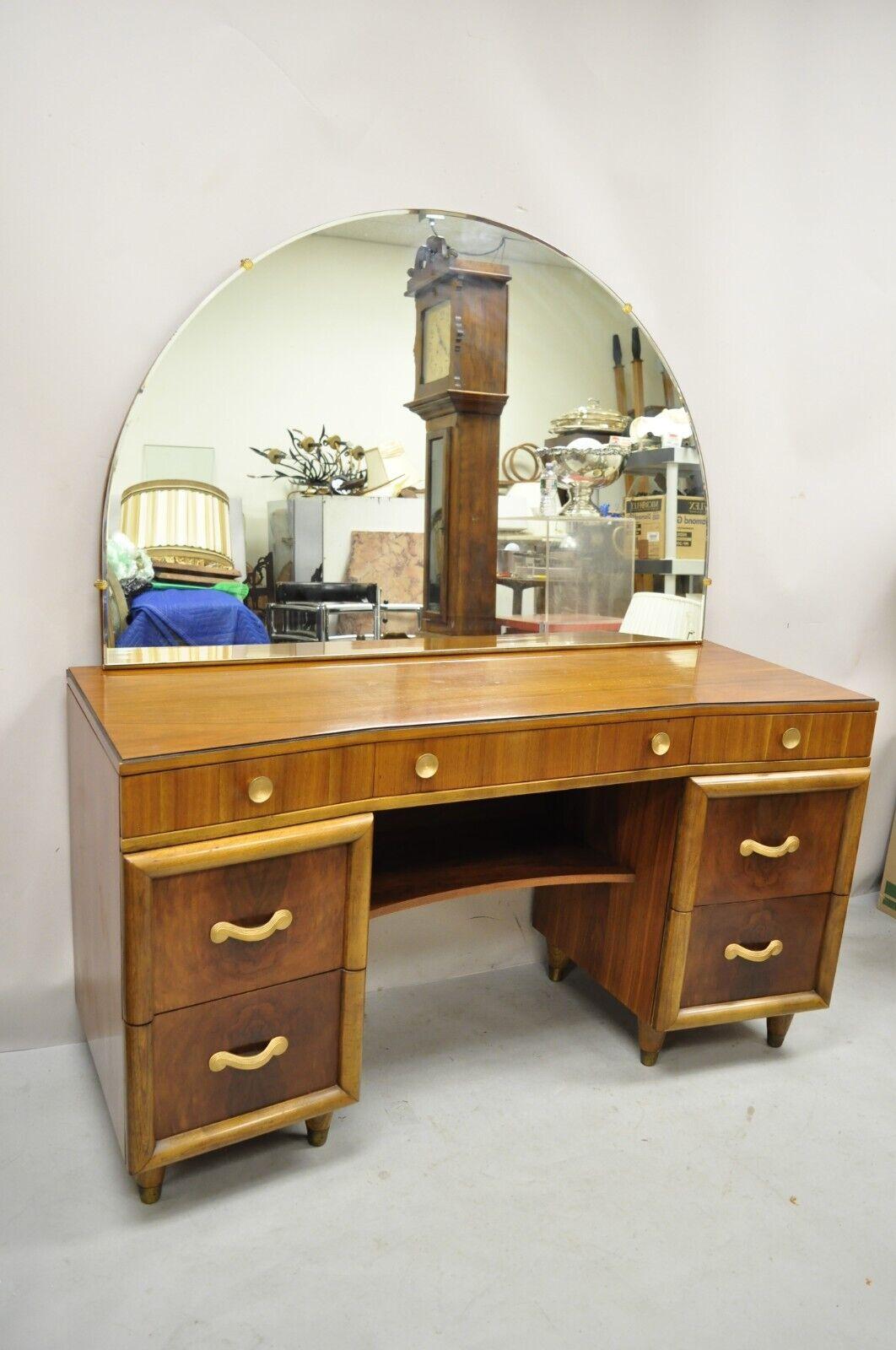 Joerns Bros Art Deco Mid Century Burl Walnut Vanity Table with Mirror. Item features arched modernist mirror, brass capped feet, black painted trim, bowed front, 7 dovetailed drawers, tapered legs. Circa early to mid 20th century.
Measurements:
