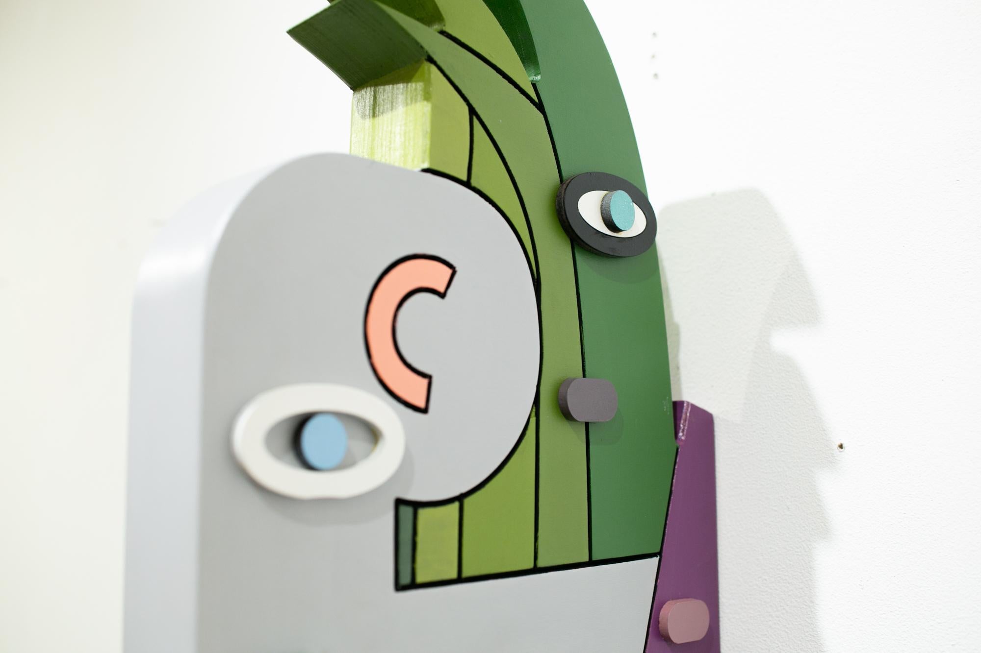 This green, purple, and grey wall-hanging abstract sculpture titled 