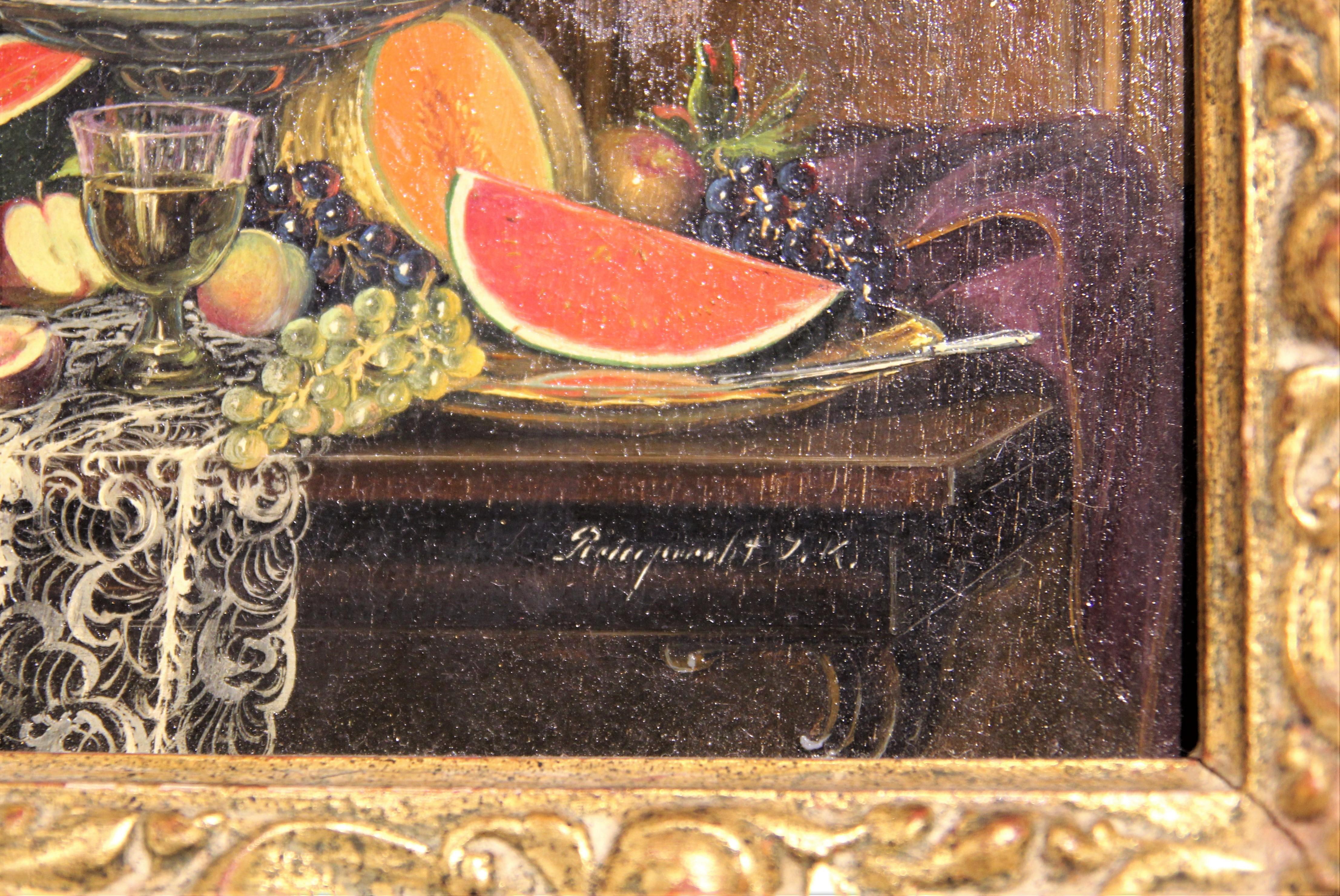 Warm toned still life painting by Hungarian artist John Karoly Reinprecht. Hyperrealistic oil painting depicting a blue and gold vase and various fruits such as watermelons, apples, grapes, oranges, and melons all arranged on a table. Signed by