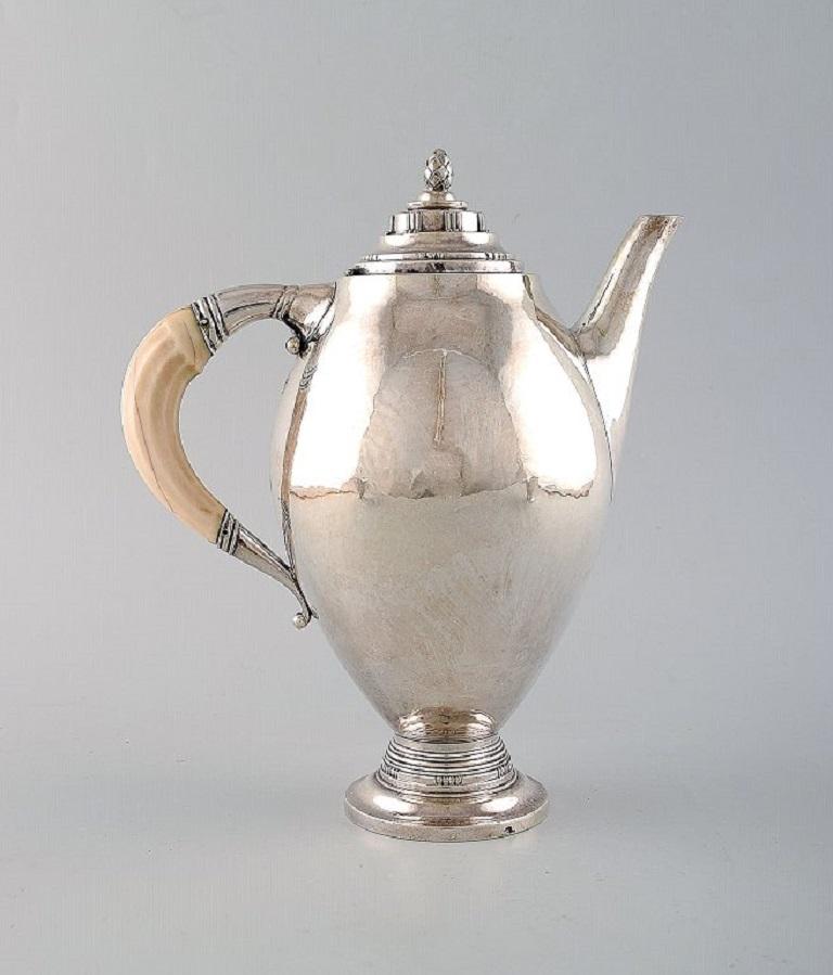 Johan Rohde for Georg Jensen. 
Rare and early coffee service in sterling silver. Coffee pot with ivory handle, sugar bowl and creamer. 
Dated 1919.
In very good condition.
Early stamp and Swedish import stamps.
The coffee pot measures: 22 x 19