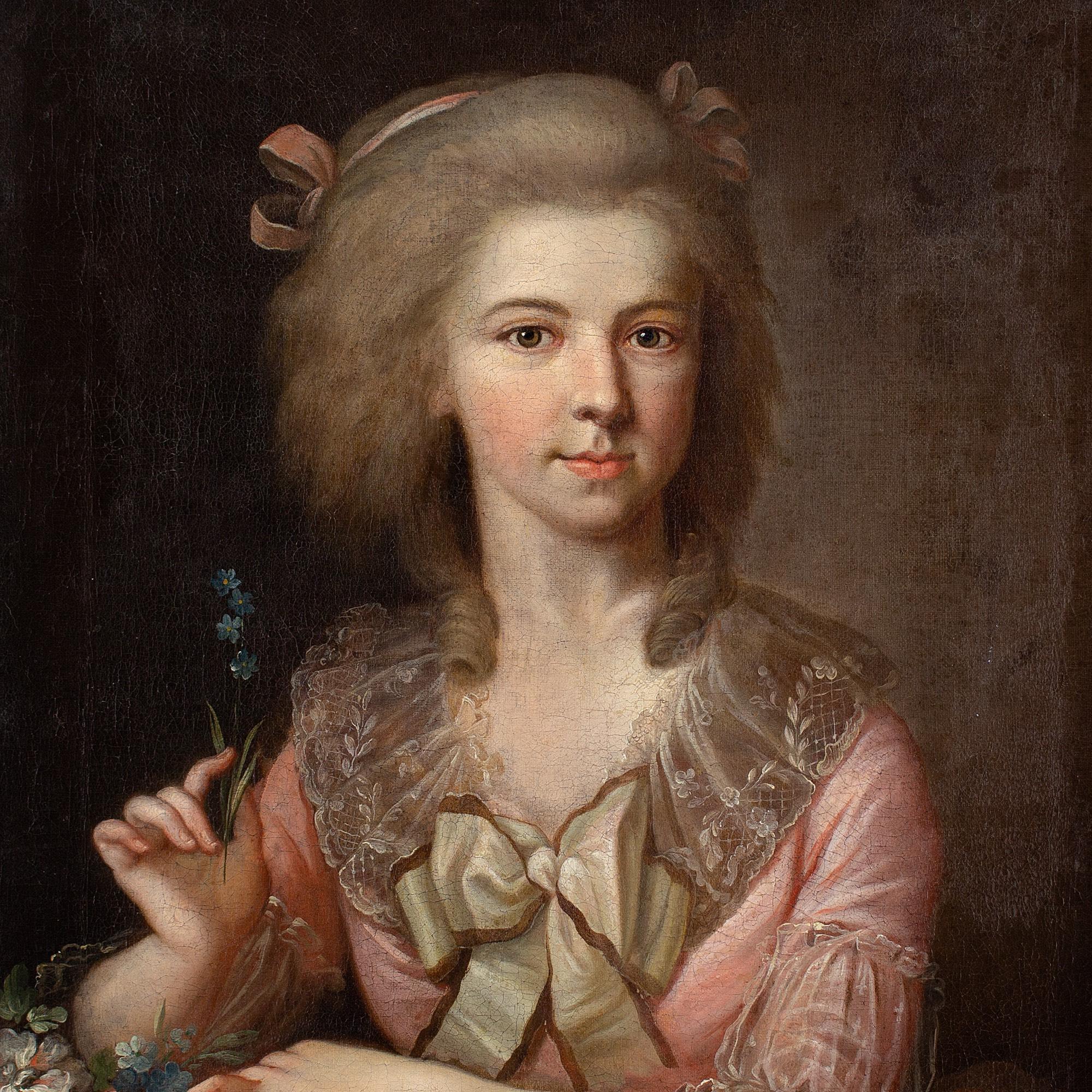 This beautiful late 18th-century portrait depicts a young lady holding forget-me-nots.

Exquisitely attired in a lavish pink dress, she’s the personification of elegance. In her right hand, a small posy of forget-me-nots, a symbol of enduring love