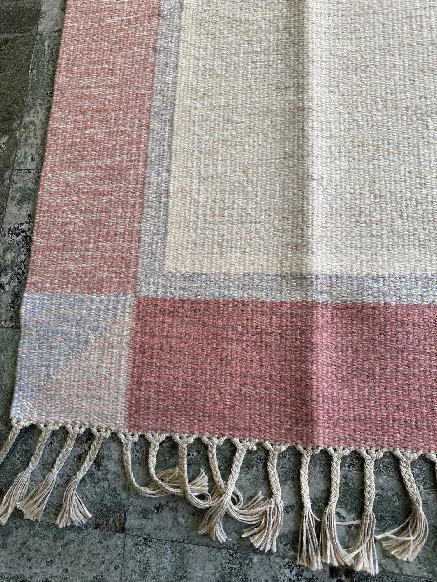 Ein wunderschöner schwedischer Flachgewebeteppich, entworfen und signiert von Johanna Ångström. Mit einer Größe von 166 x 233 cm zeigt dieses Stück die raffinierte Ausgewogenheit von Muster und Farbe, die für die skandinavische Textilkunst der Mitte