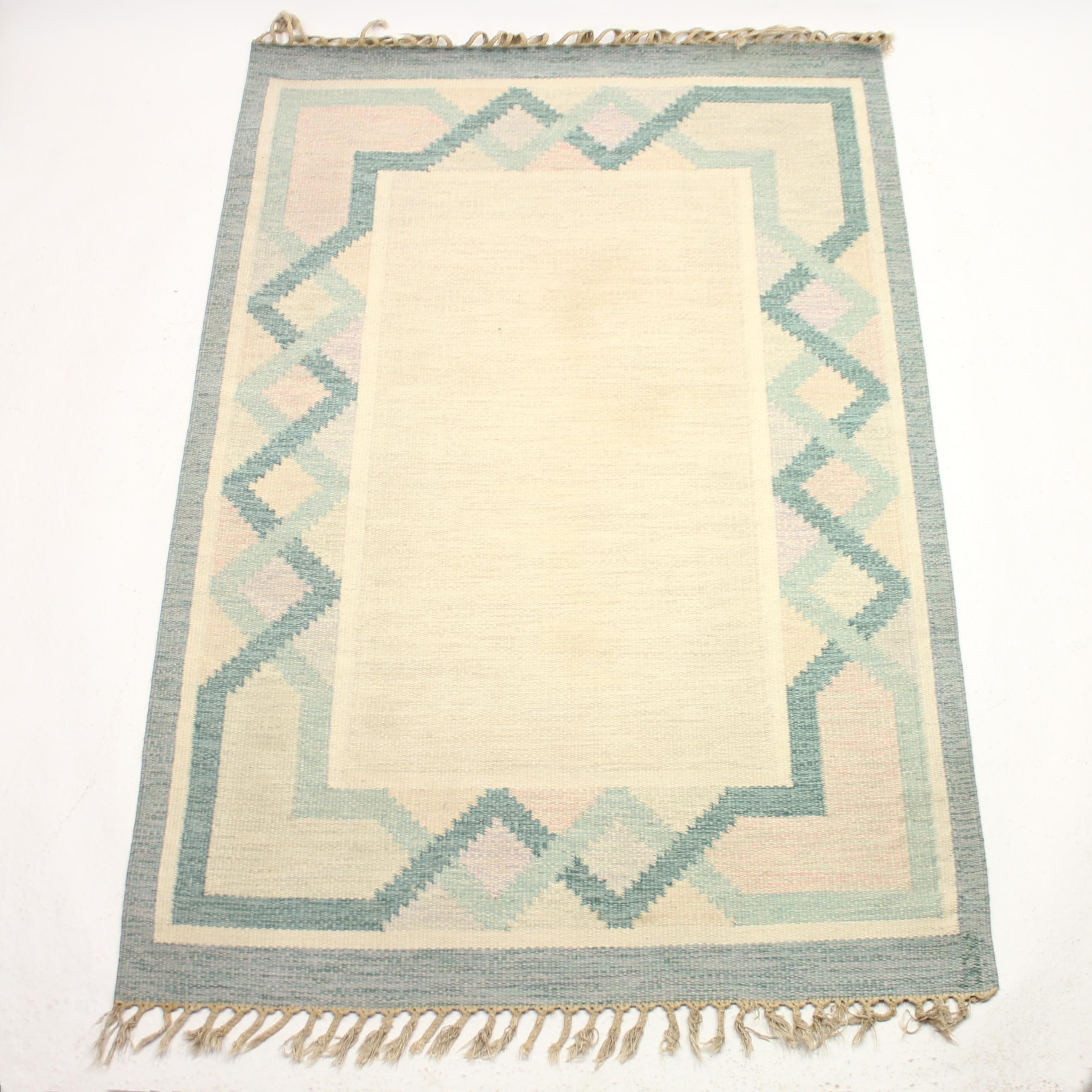 Swedish flat weave Röllakan carpet from the 1950s by Johanna Ångström. Marked Å (for Johanna Ångström) in the bottom right corner. Main colors are green and beige with a variety of patterns and shapes in pink, beige and green on a beige bottom/base.