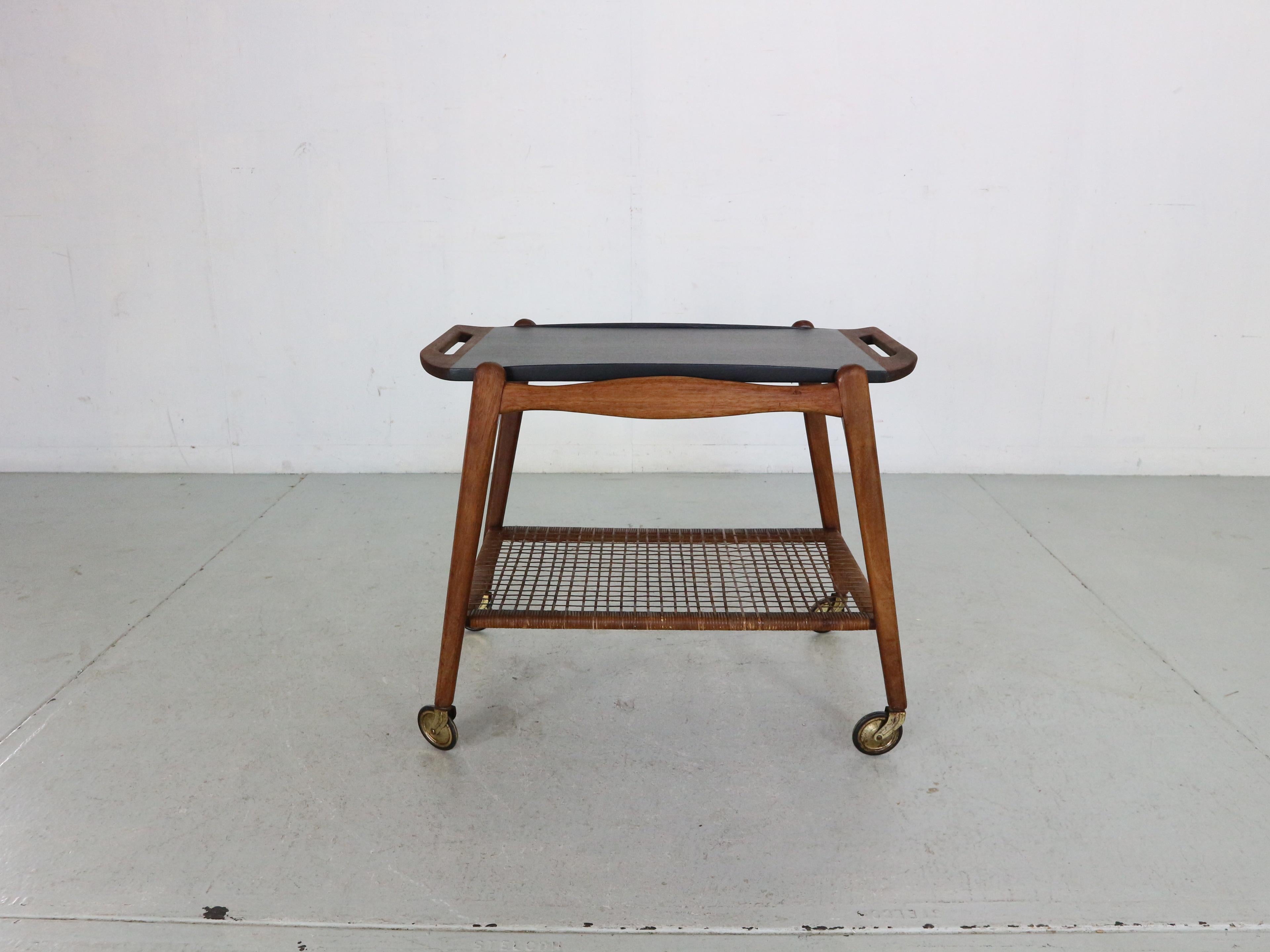 Teak serving trolley by Johannes Andersen, 1960s Danish modern serving cart in teak and cane attributed to Johannes Andersen for CFC Møbler. 
Removable teak tray with handles in solid teak. The top has been professionally painted in black