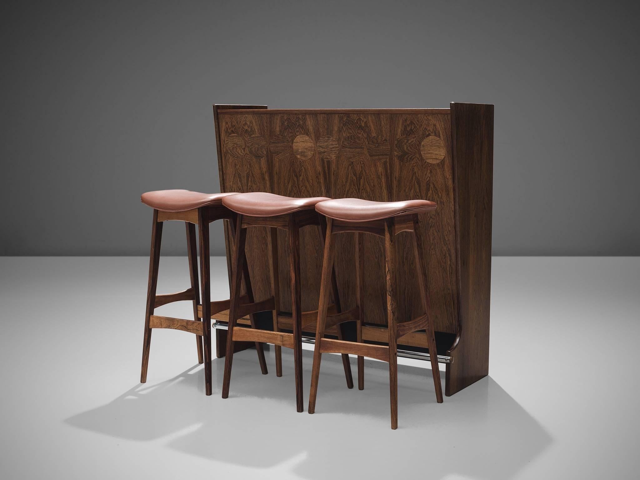 Johannes Andersen, bar in rosewood, glass and steel for Skaaning & Søn, model SK 661, Denmark, 1960s and three bar stools by Eric Buck.

Stools are also by Andersen and are not included in the price

This wonderful little rosewood bar is designed by