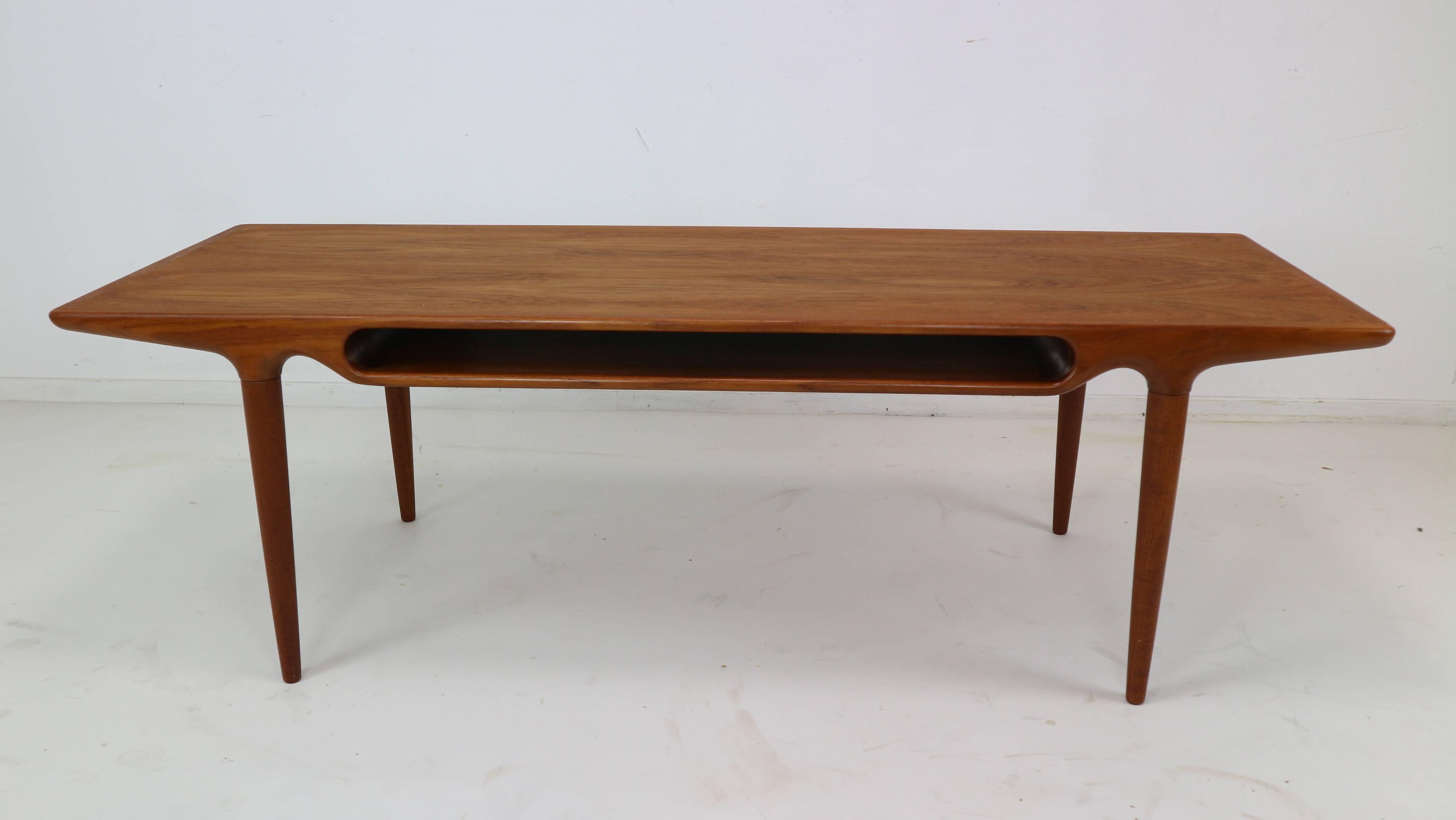 A superb teak coffee table by Johannes Andersen for C.F.C. Silkebørg. Of any Danish designer, Andersen's concepts are some of the most organic and unique. The pass through shelf on this piece not only gives the table its unique appearance, it also