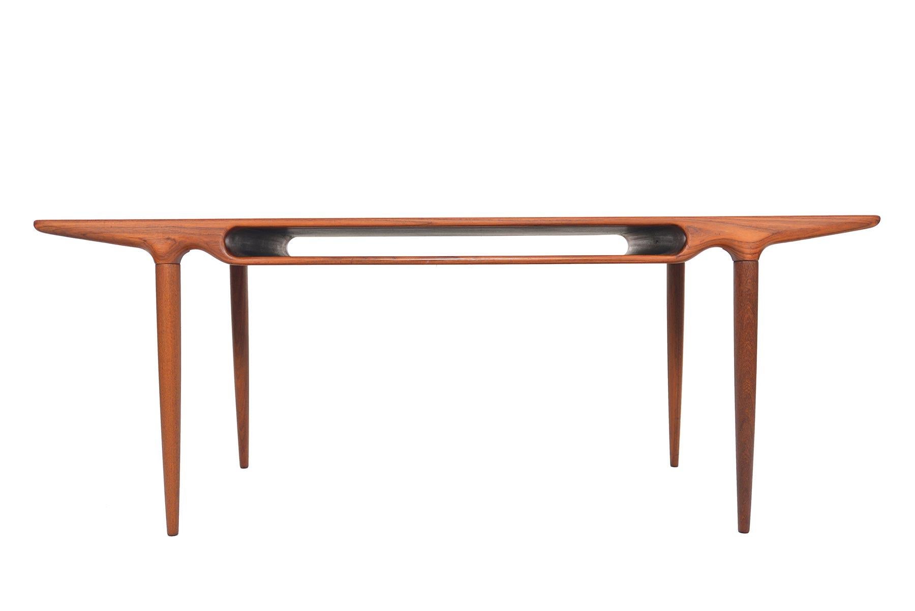 This Danish modern midcentury coffee table in teak was designed by Johannes Andersen for CFC Silkeborg Møbelfabrik in the 1960s. Expertly built, this gorgeous piece features solid teak legs which are seamlessly joined to the table top. The table