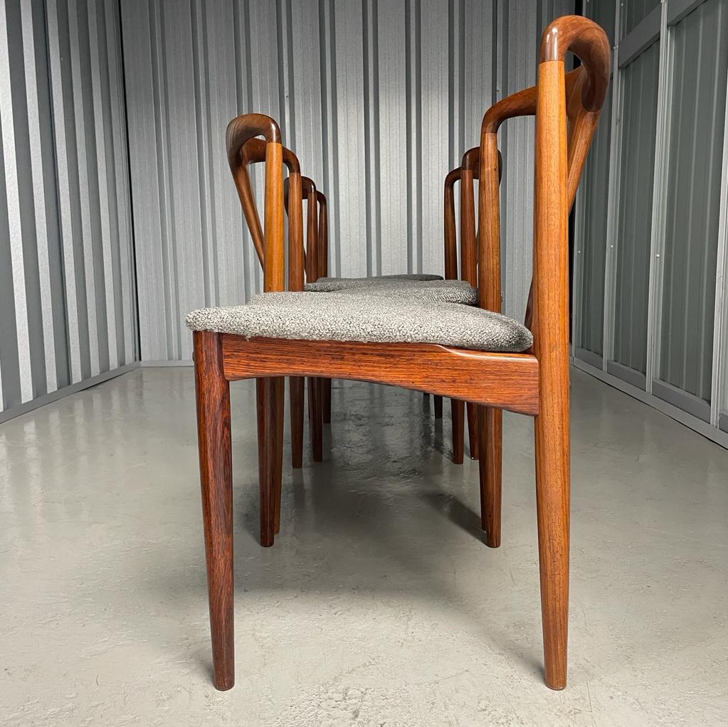 Experience timeless elegance with the Johannes Andersen rosewood dining chairs by Uldum Møbelfabrik. Crafted from premium rosewood and adorned with grey boucle upholstery, these four chairs bring sophistication to any dining space. Their versatile