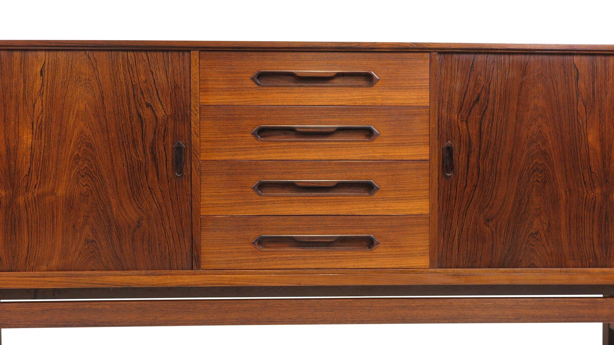 Finely crafted mid-century rosewood credenza designed by Johannes Andersen for Silkeborg Møbelfabrik, Model 93, circa 1960, Denmark. The sideboard is handcrafted from book-matched old-growth rosewood with a pair of tambour doors and center drawers