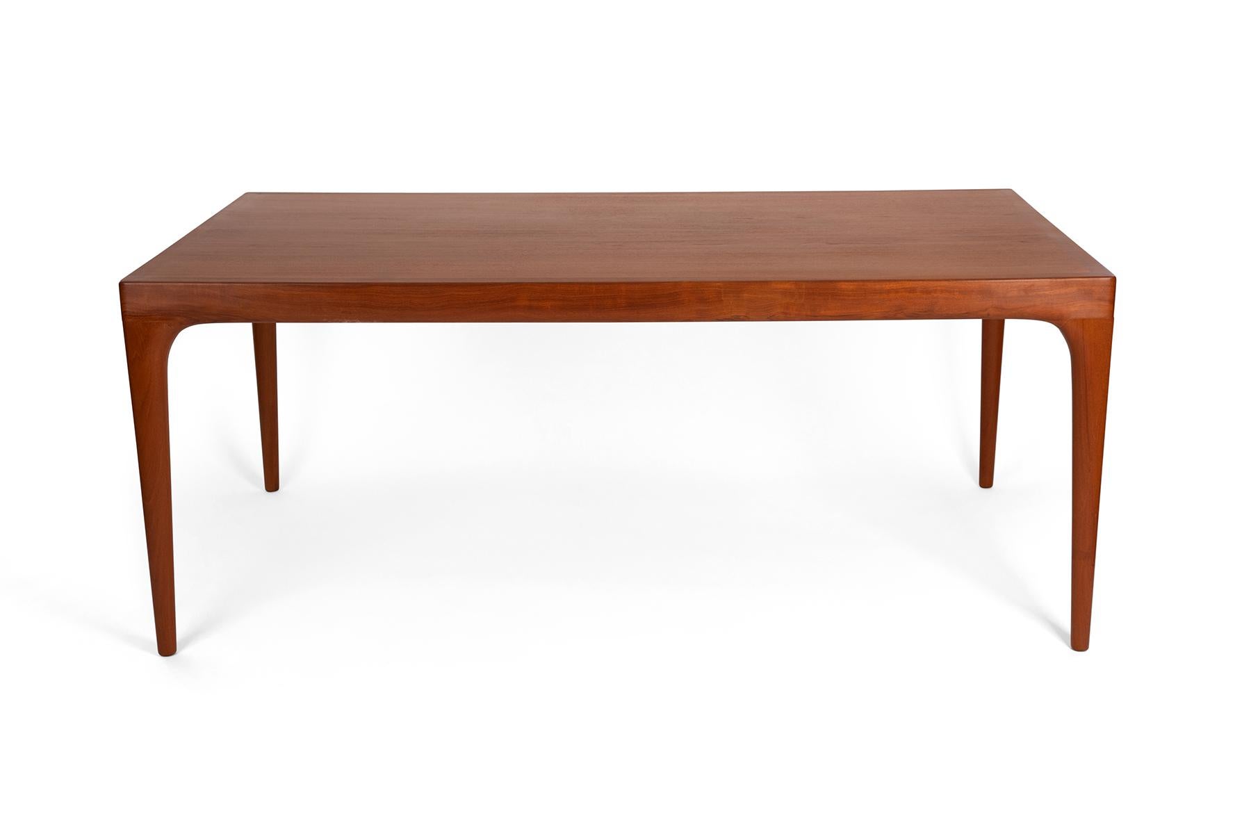 Newly refinished dining room table designed by Johannes Andersen circa early 1960's.
The table features sculpted solid teak legs and an extendable shelf that is cleverly stored underneath and can be pulled out when you need extra space for serving