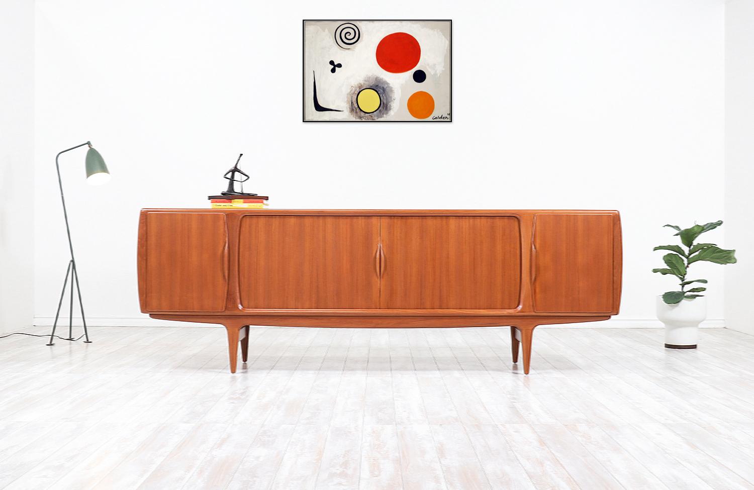 One of our most monumental and skillfully crafted credenzas by Danish designer, Johannes Andersen in collaboration with Uldum Møbelfabrik in Denmark, circa 1960s. Our striking teak credenza features a flawless set of tambour-doors with sculpted