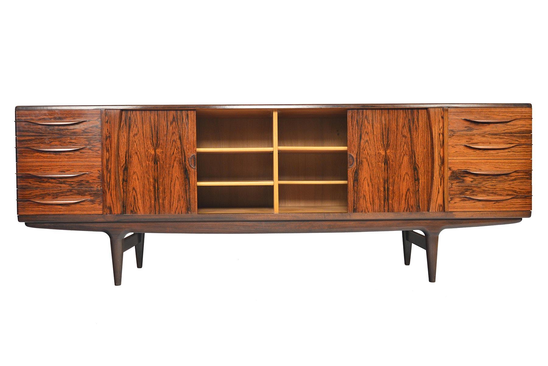This breathtaking large rosewood credenza model U15 was designed by Johannes Andersen for Uldum Møbelfabrik in the 1960s. This beautiful piece offers soft banding and a drawer design that wraps to the side of the piece for organic profile. Two