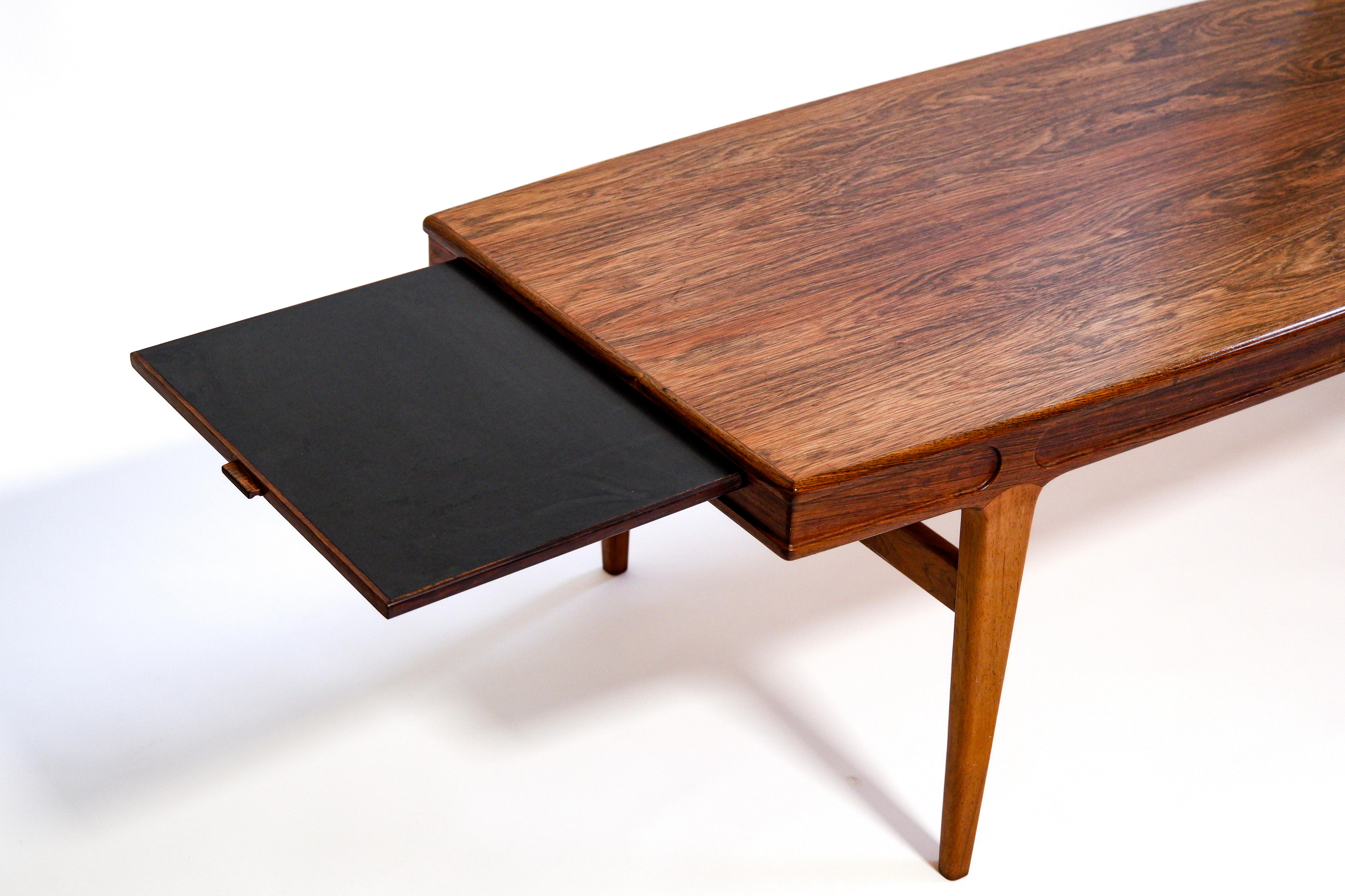Large coffe table in beautifull brazilian wood with a double table extension that comes out on both sides of the table. Both extension are 33 cm each. The table has been designed by Johannes Andersen in danemark and produced in the 60's. The wood is