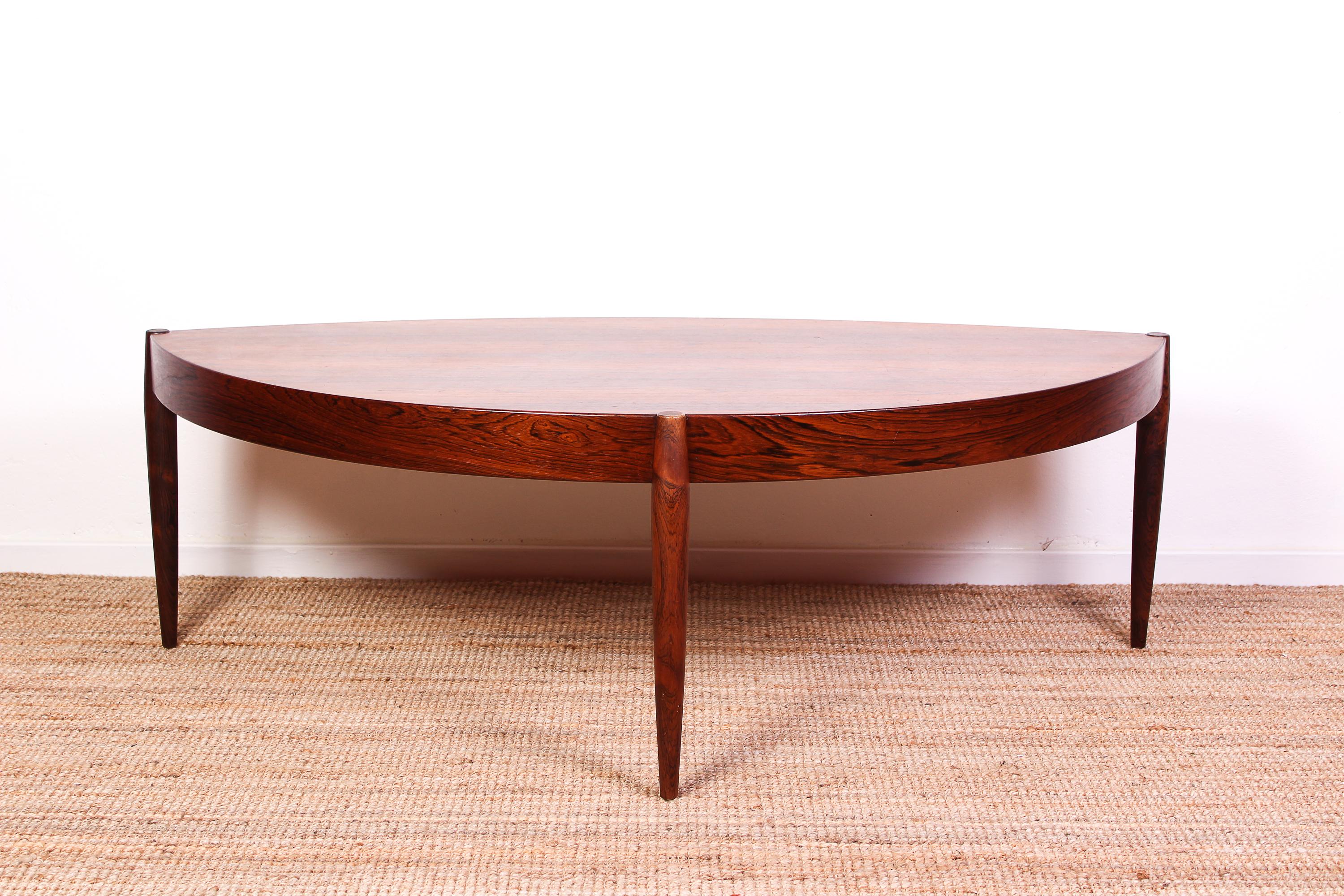 This rosewood coffee table is designed by Danish designer Johannes Andersen. The table has three legs and large top. Great design and quality by a well-known designer of the period. The table is in excellent vintage condition with only small signs