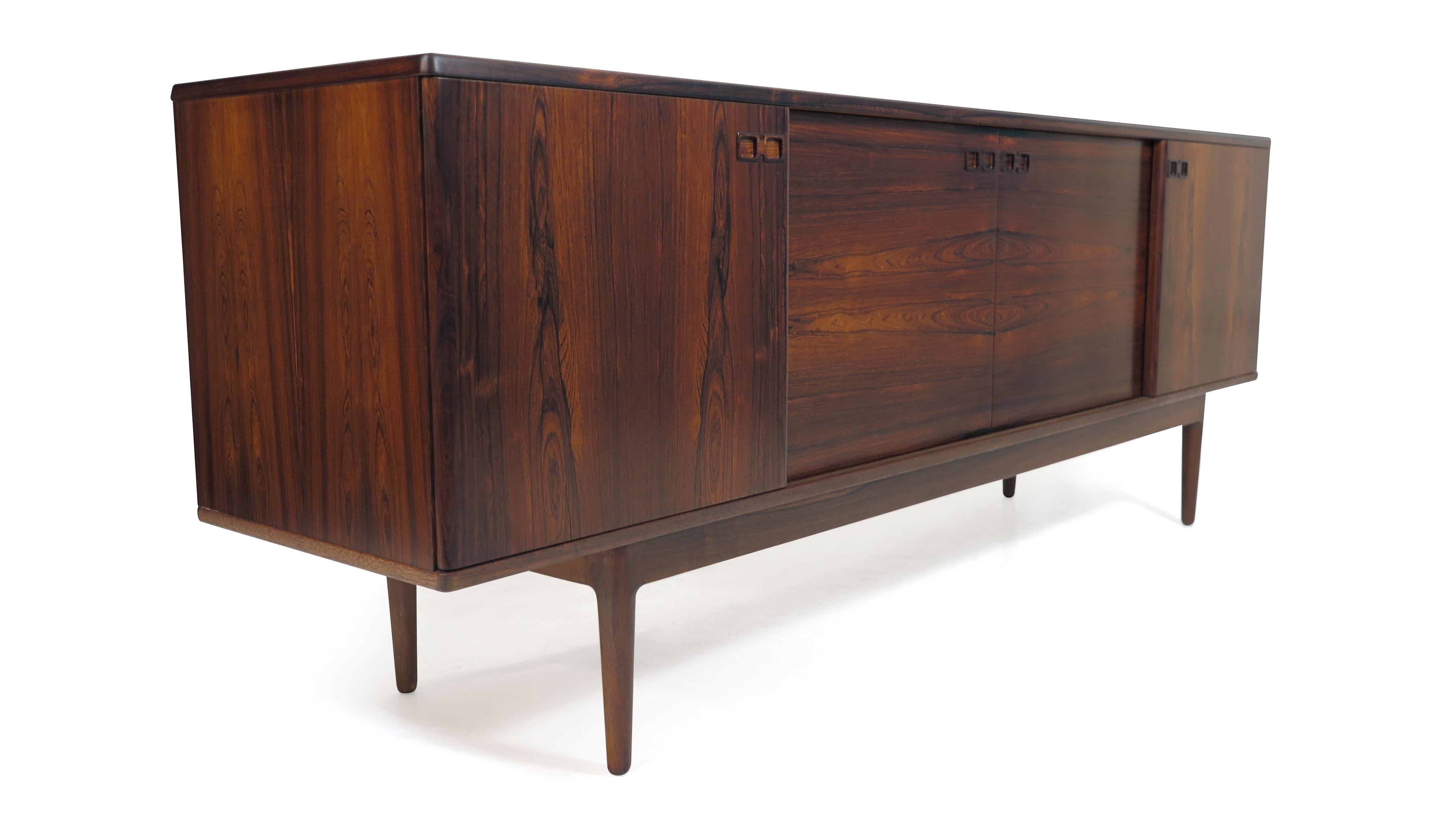 
Mid-century Danish sideboard designed by Johannes Andersen for Christain Linneberg, circa 1960 Denmark. The cabinet is finely crafted of Brazilian rosewood features stunning pattern matched grain on four sliding doors with sculpted handles, which